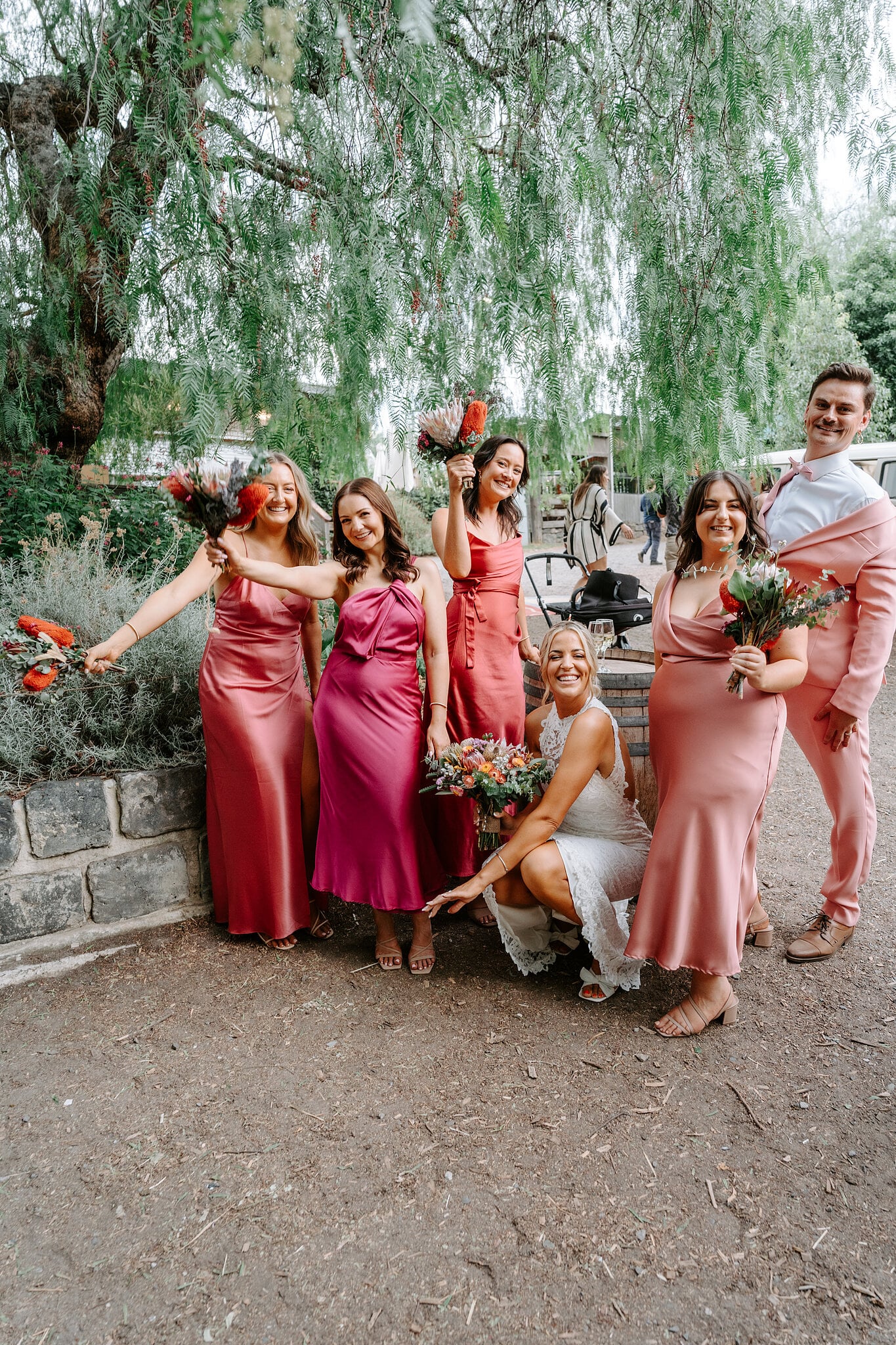 Emma and her bridal party in pink and red satin strike a pose in the farmyard.
