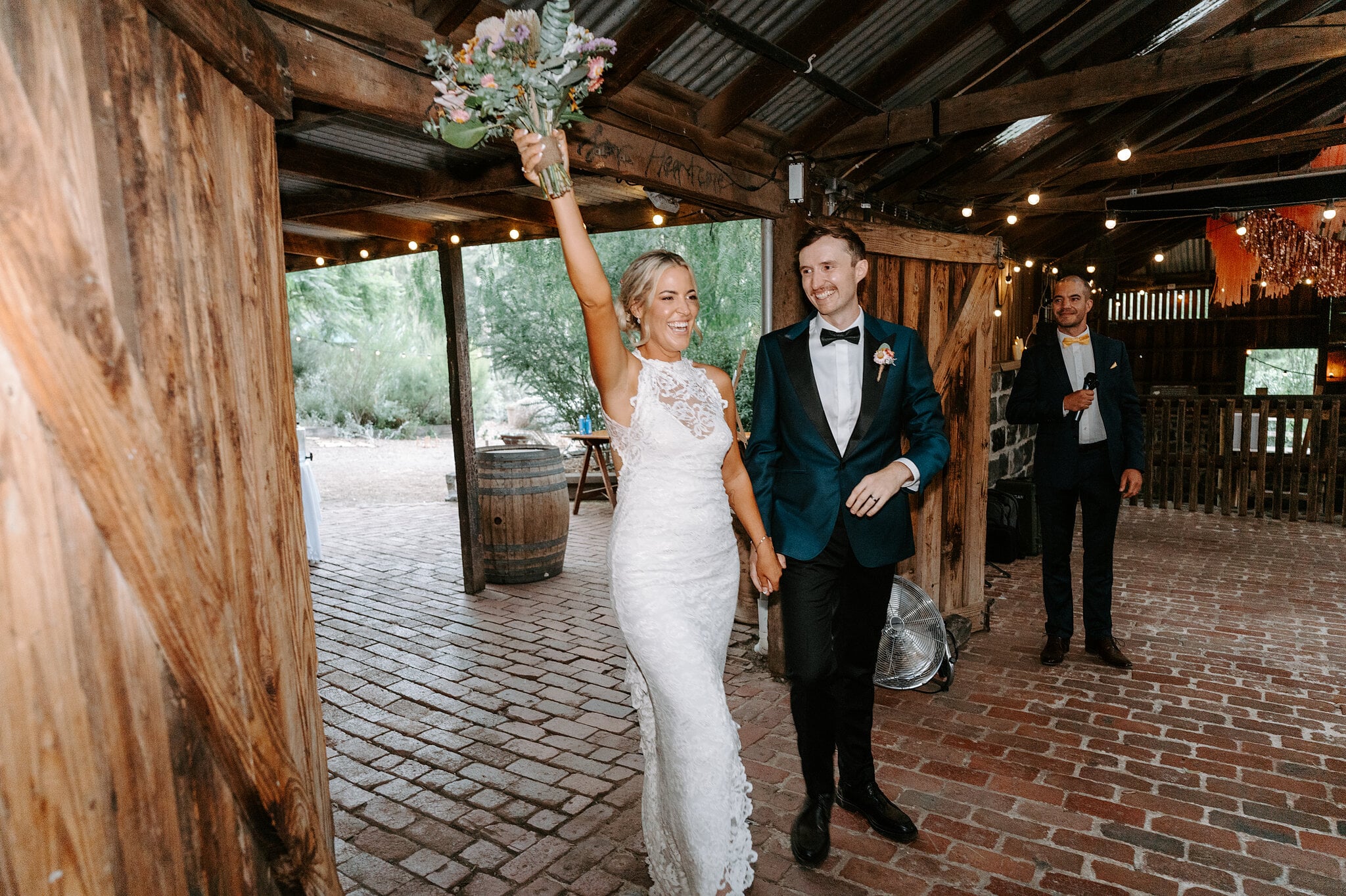 Emma raises her bouquet as she and George make their entrance into the Barn.