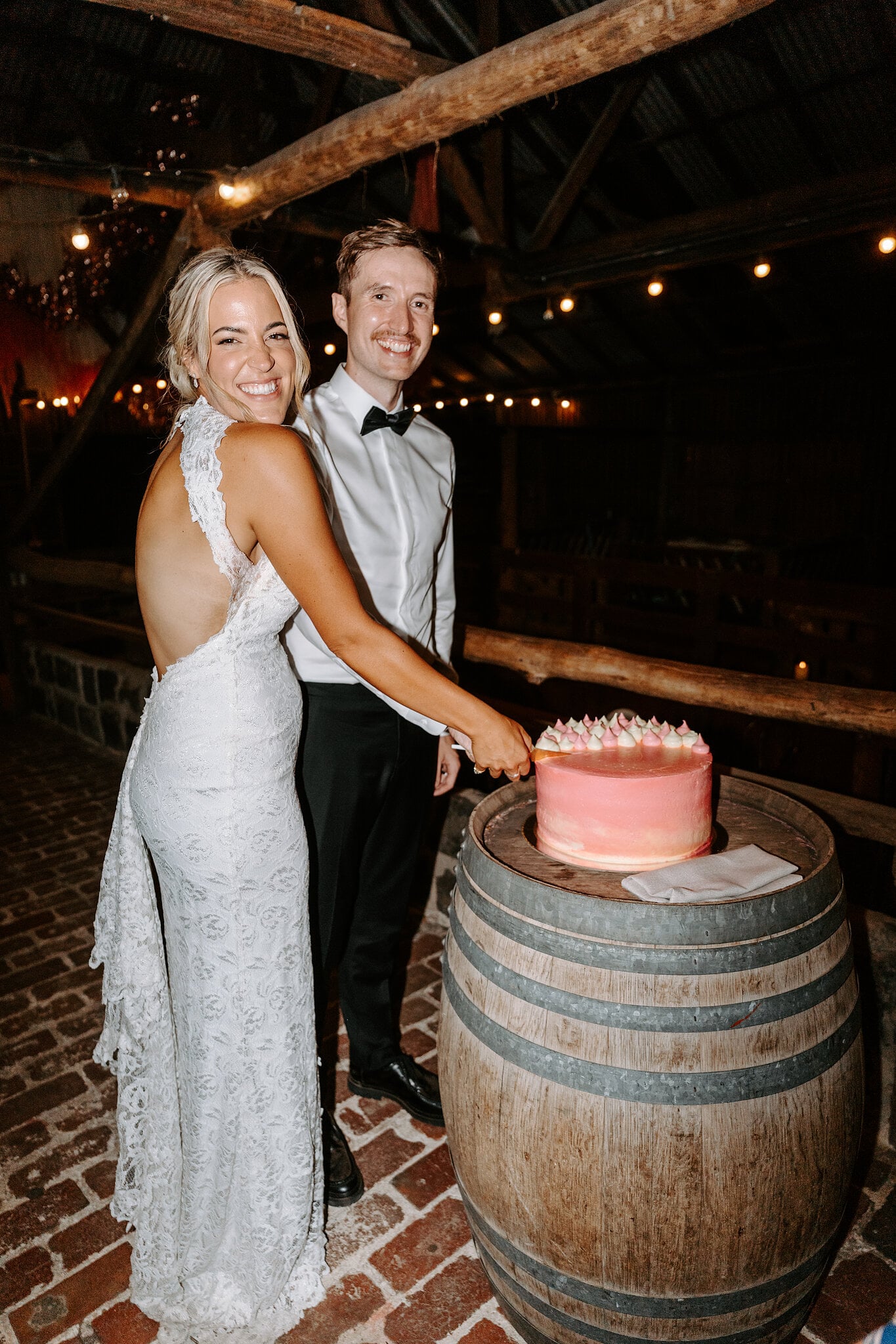 Emma and George cut their pink cake on a wine barrel in the Barn.