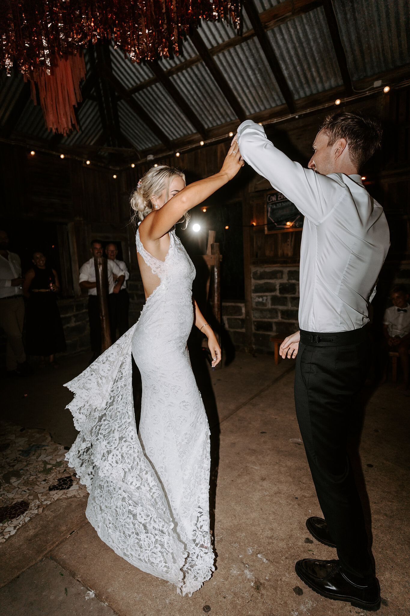 George twirls Emma during their first dance under strings of lights.