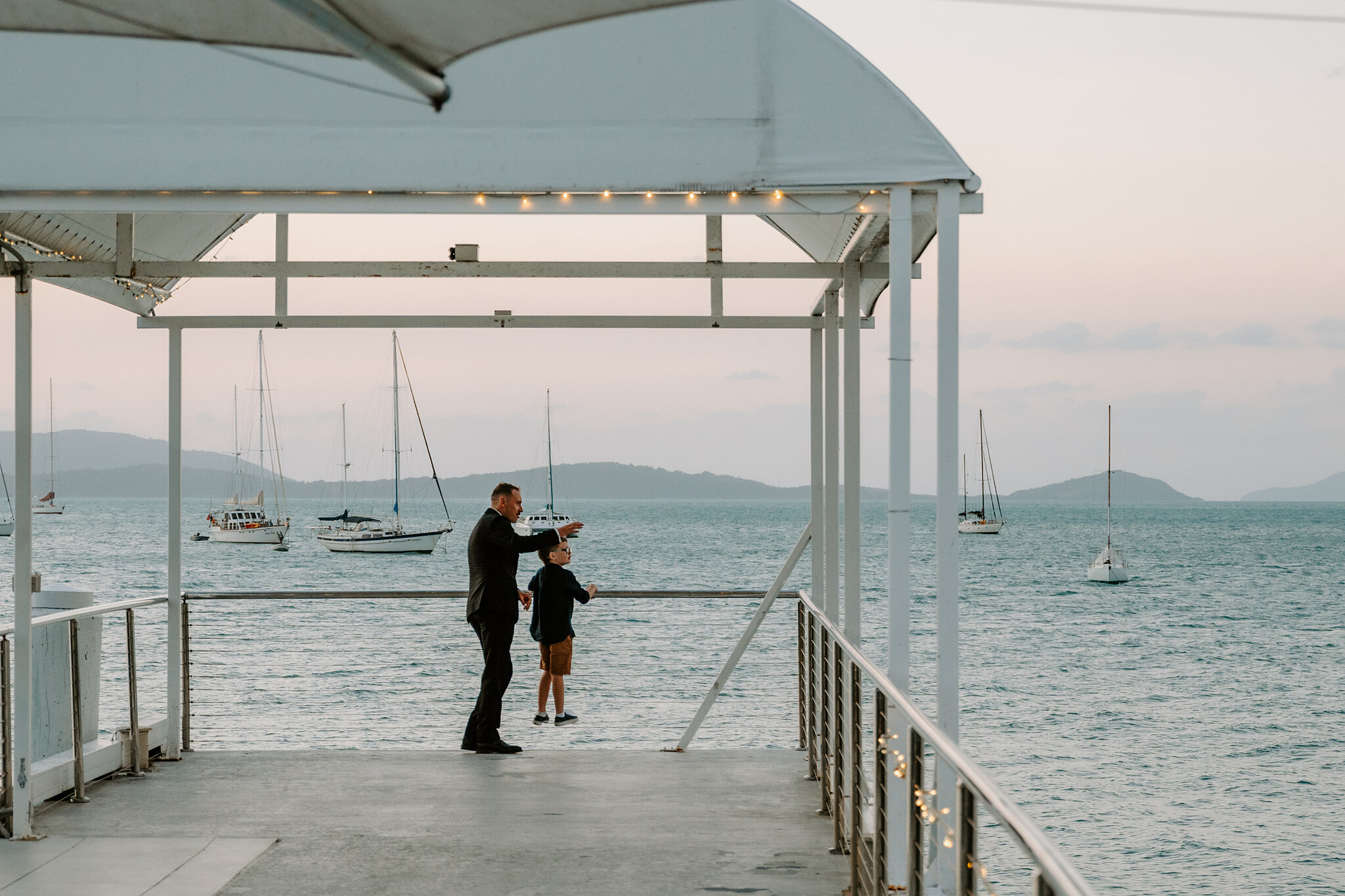 Brendan and a young guest look out from the end of the jetty at dusk.