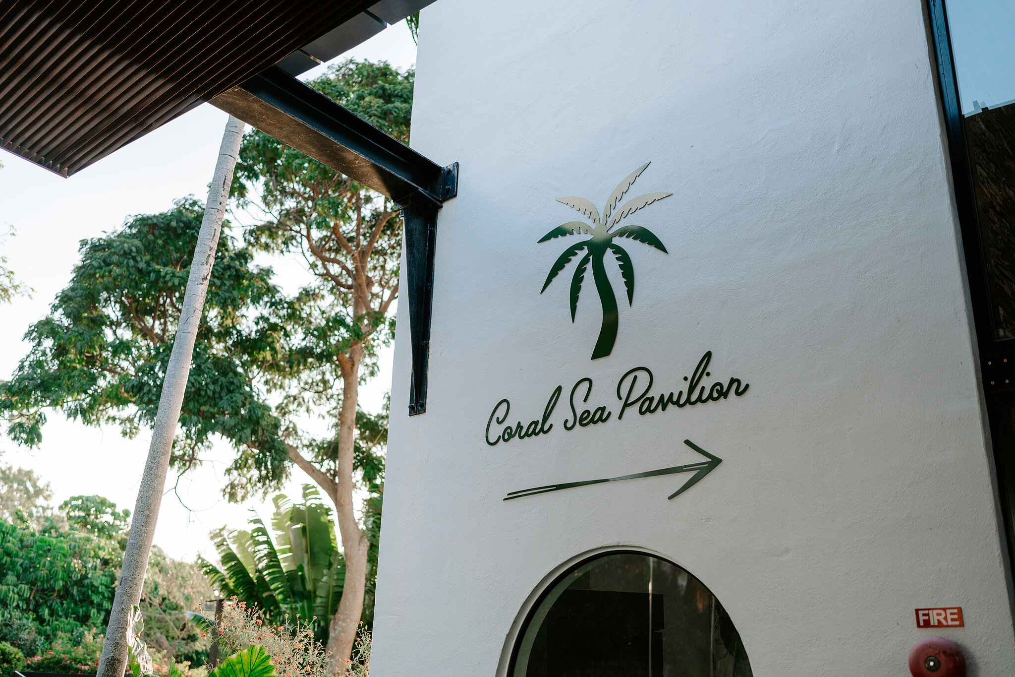 The Coral Sea Pavilion sign at Coral Sea Resort, a palm painted on the white wall.