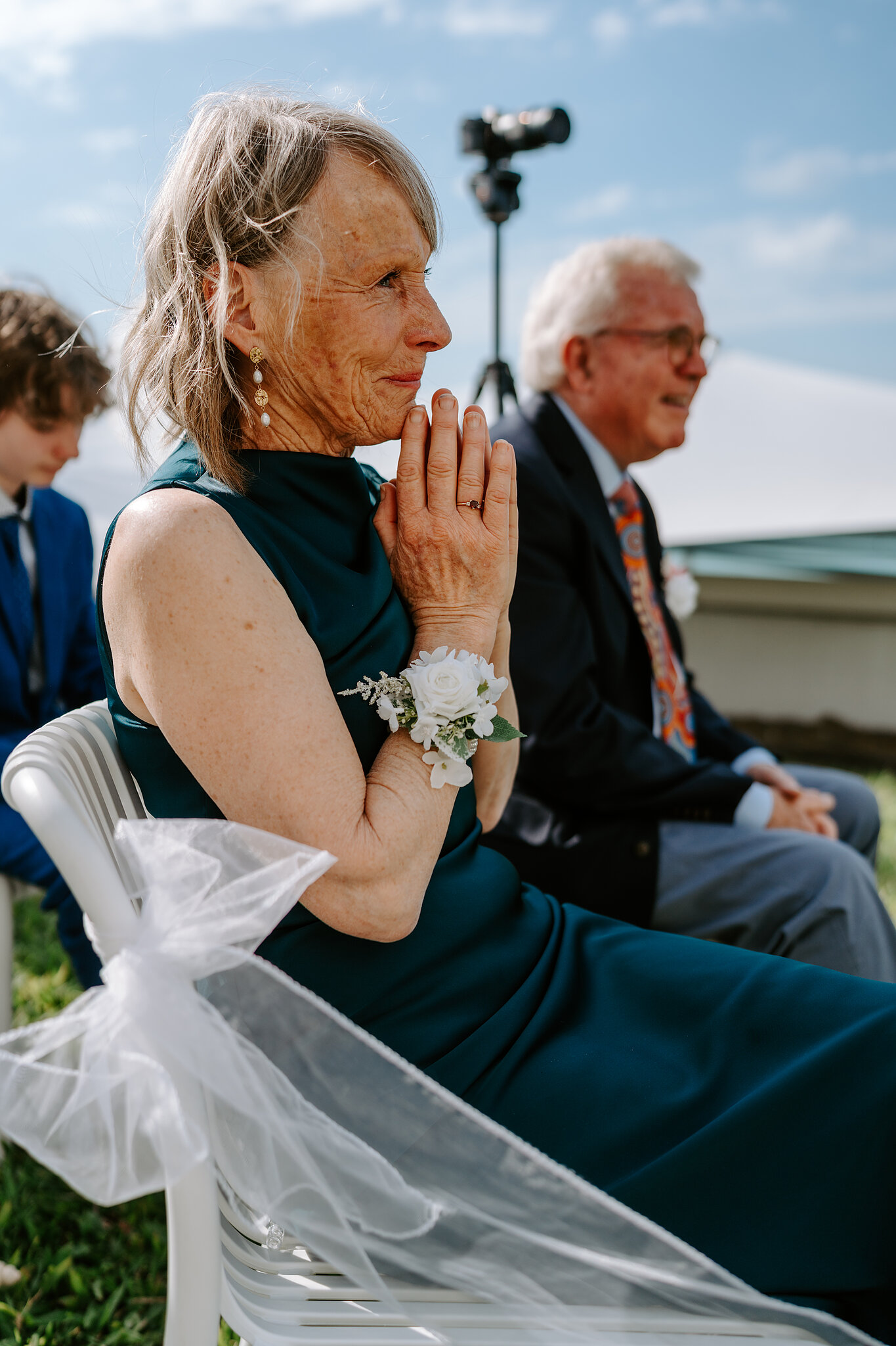 Brendan’s mum, a white corsage on her wrist, clasps her hands during the vows.