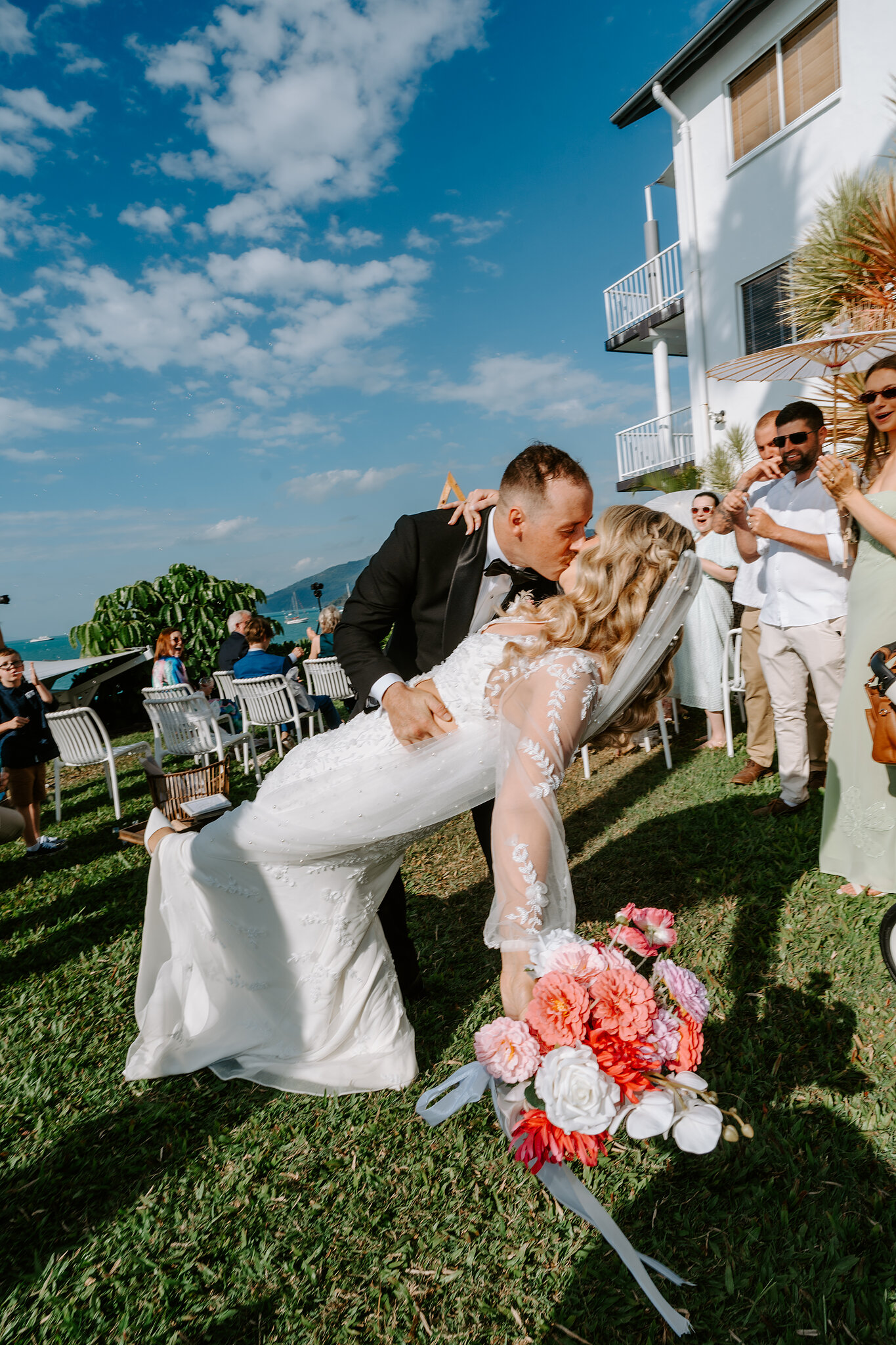 Brendan dips Anna for a kiss as her bright bouquet swings out.