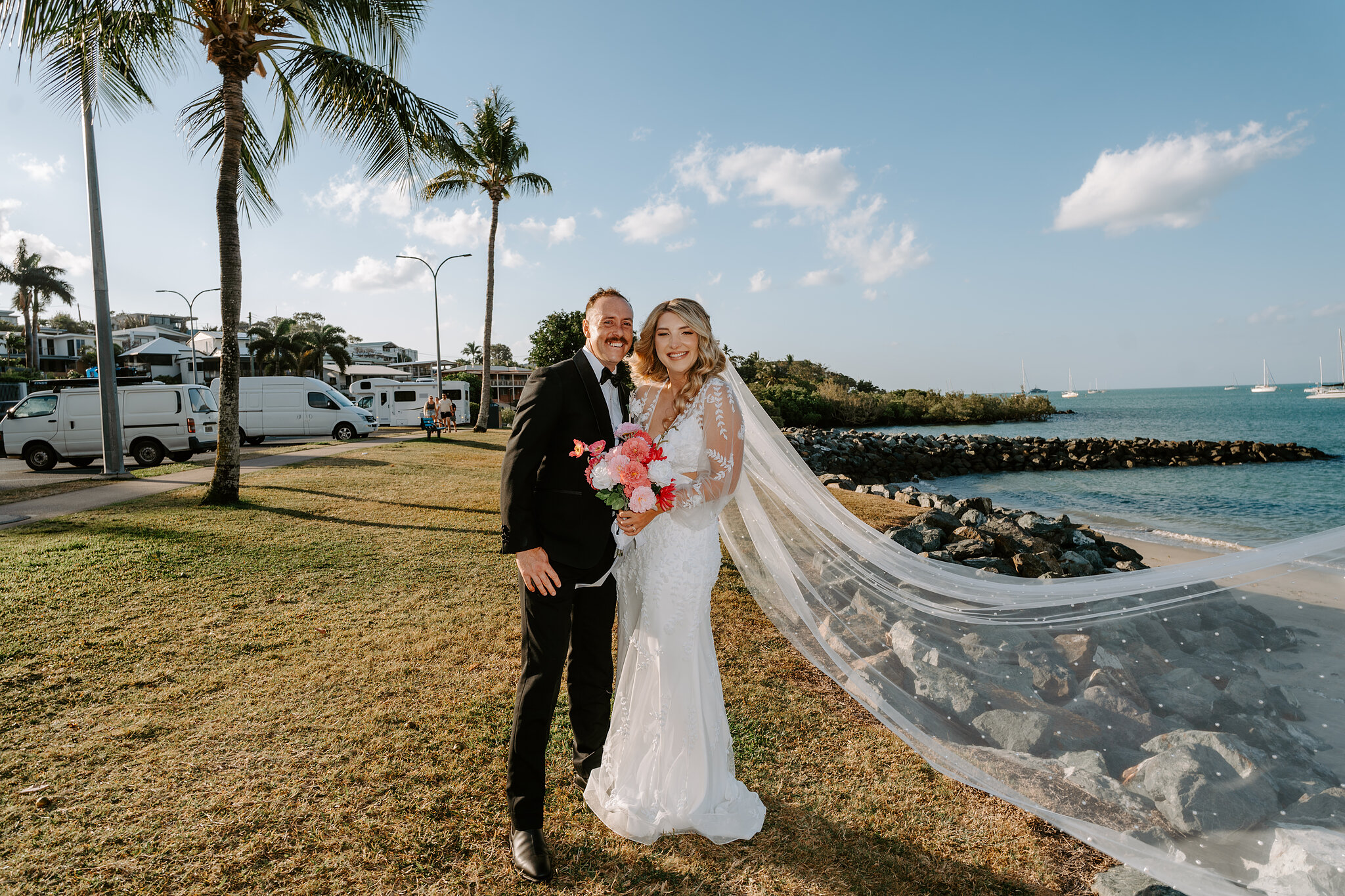 Anna’s long veil streams out in the breeze beside the rock wall as she and Brendan smile.