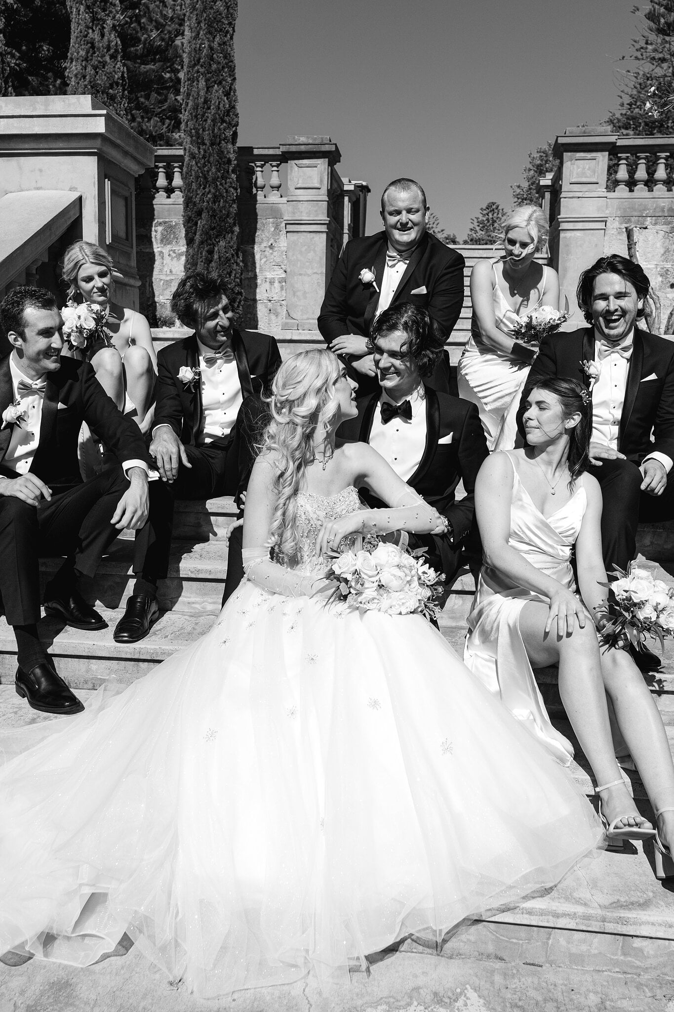 Black and white of the bridal party laughing on the old terrace steps in Cottesloe.