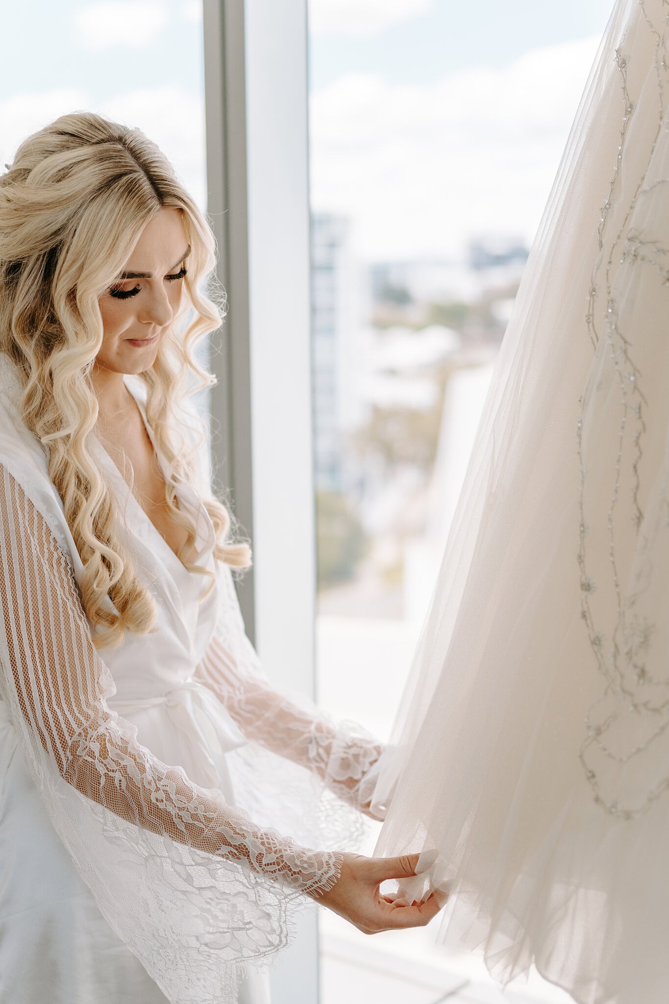 Claire runs her fingers along the beaded tulle of her gown hanging by the window.
