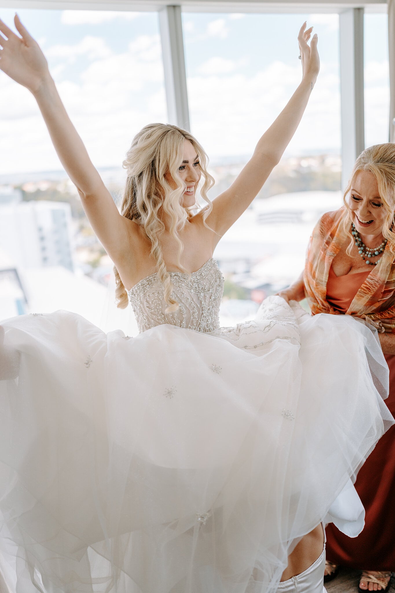 Claire throws her arms up in her beaded gown as her mum fluffs the tulle skirt.