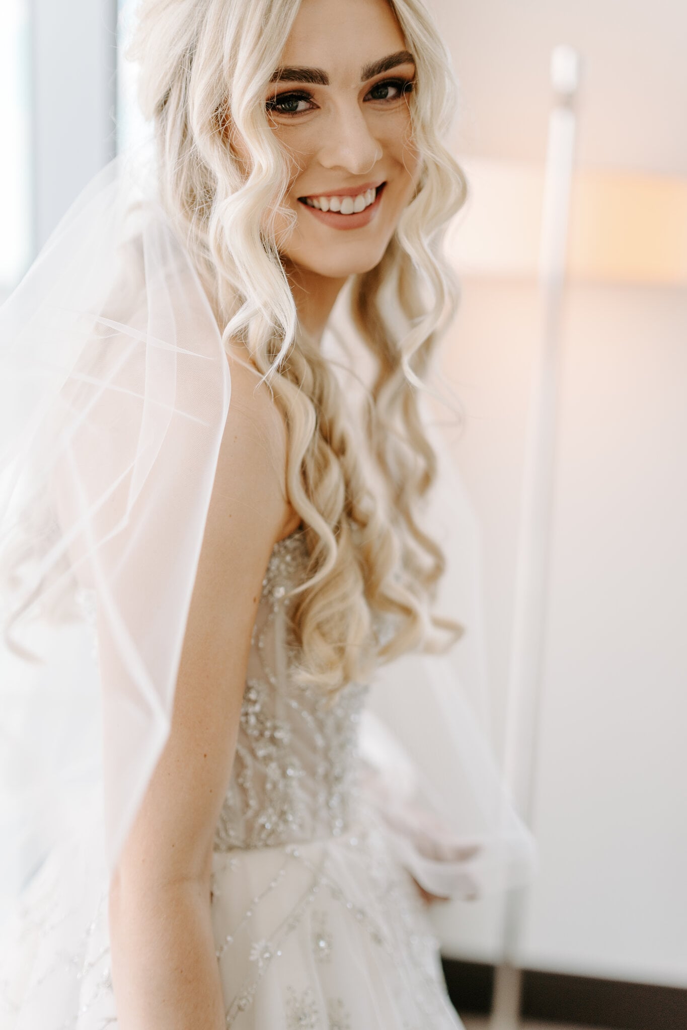 Claire beams over her shoulder, sheer veil around her blonde curls.