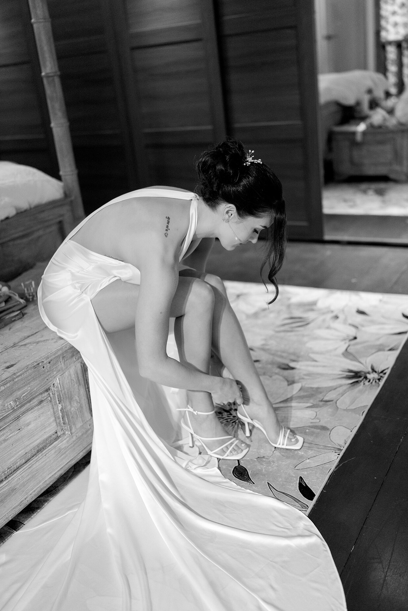 Emma fastens her strappy heels in her satin gown, in black and white.