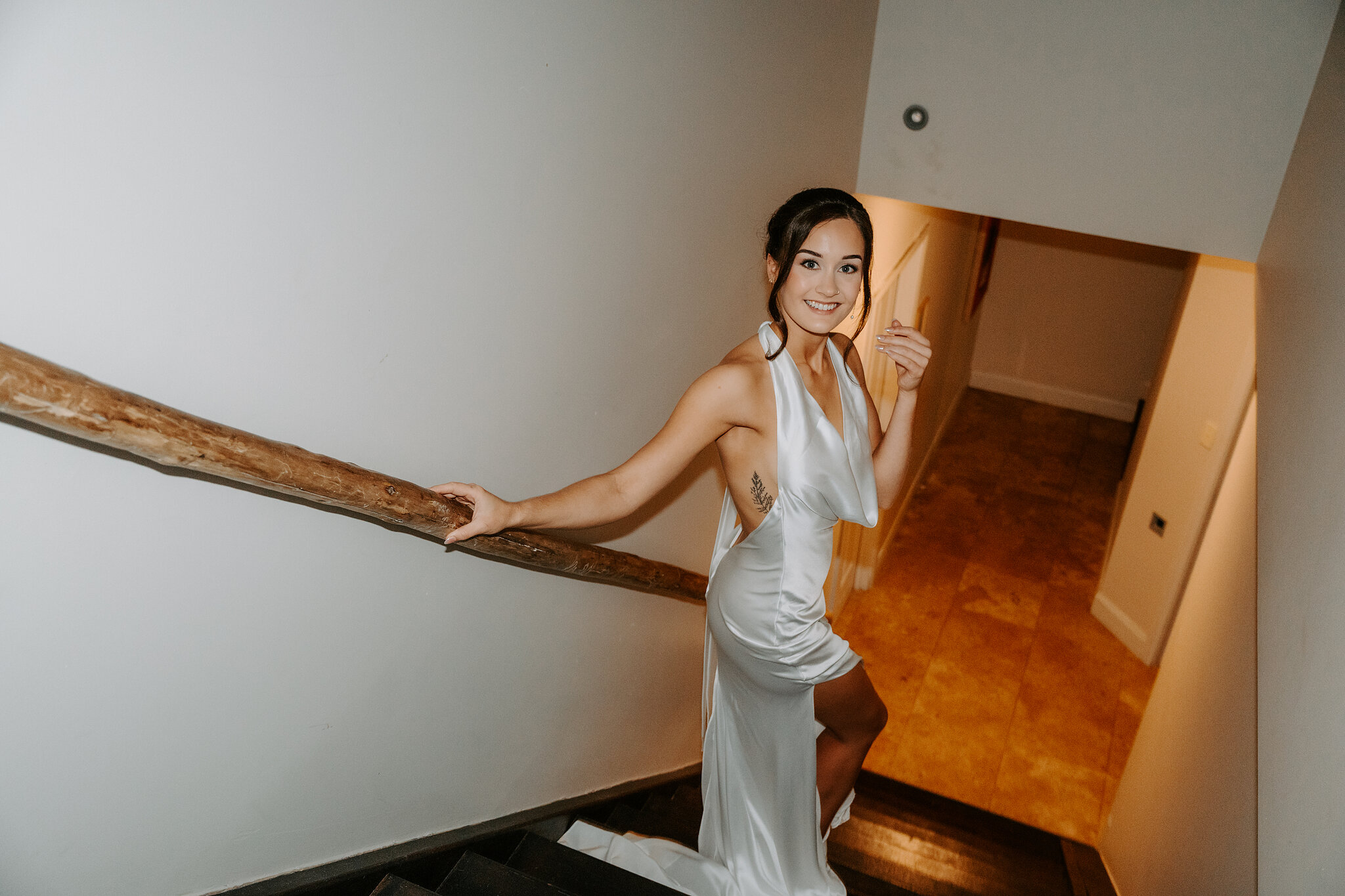 Emma smiles up from the staircase, one hand on the timber rail.