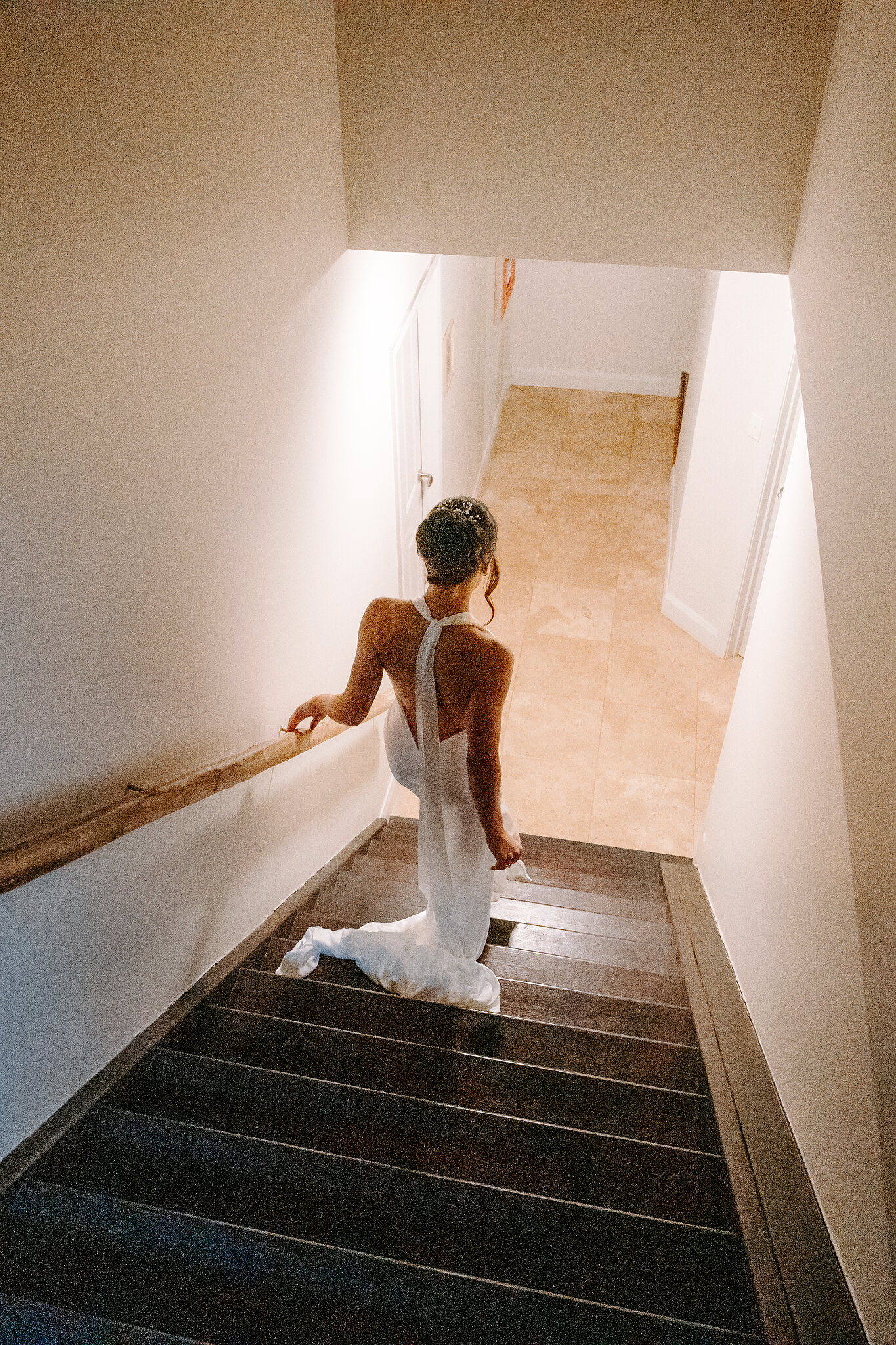 Emma walks down the stairs towards the light, her train following behind.