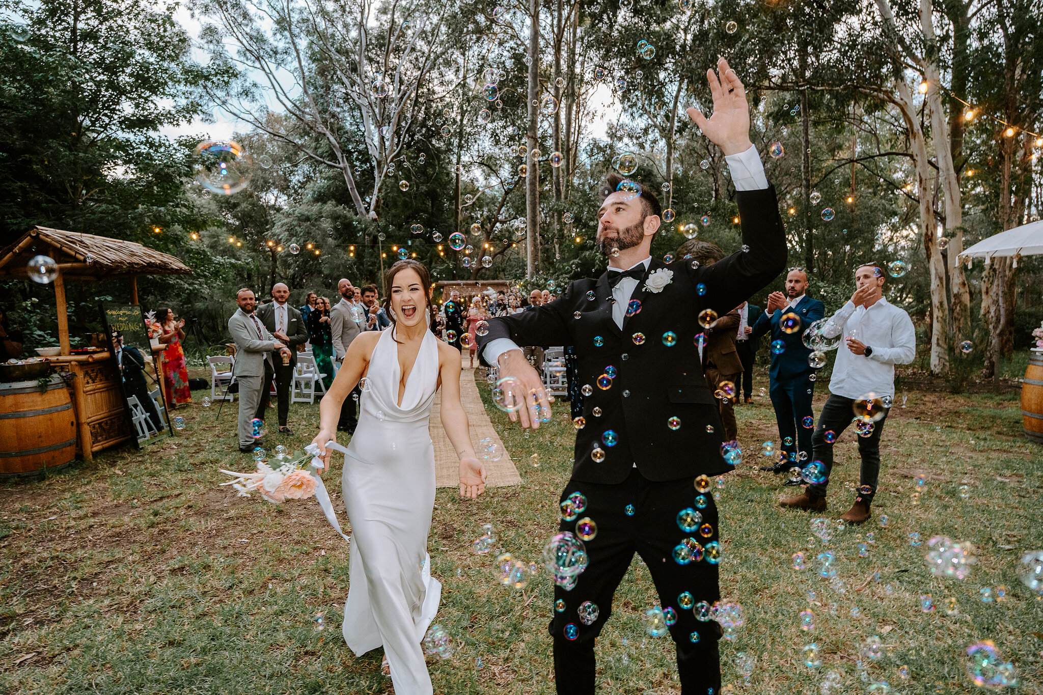Dave punches the air as he and Emma head back up the aisle through bubbles.