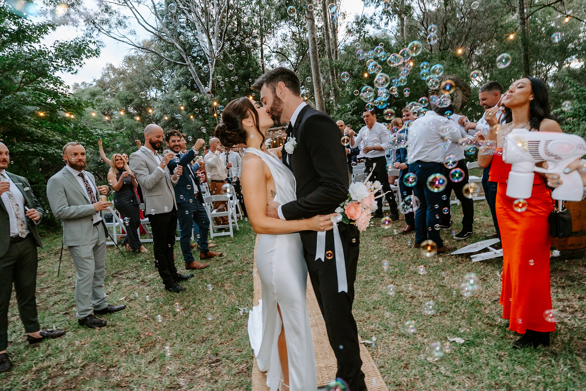Emma and Dave kiss in a cloud of bubbles as guests cheer around them.