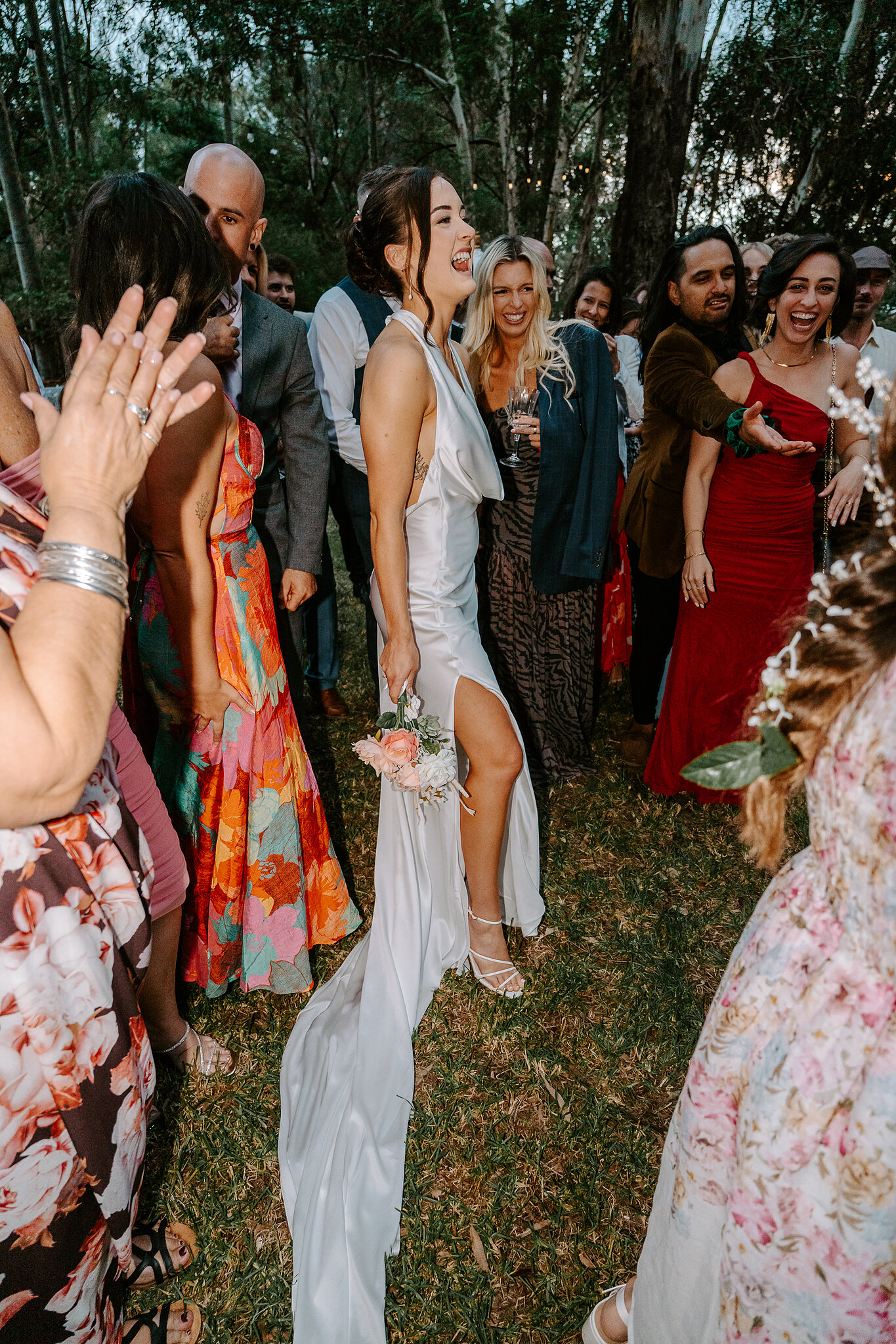 Guests in bright florals cheer and clap around Emma after the ceremony.