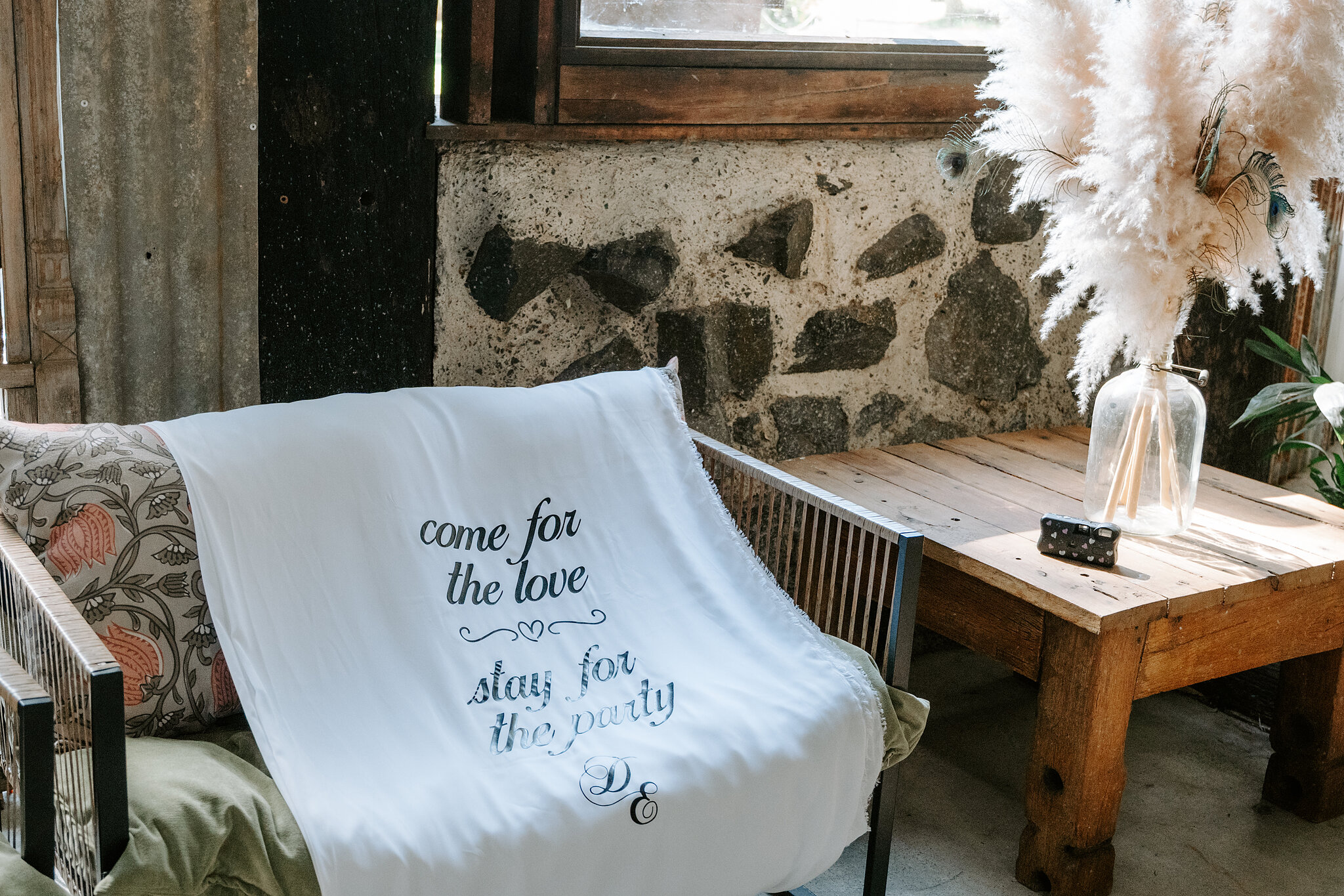 A throw reading “come for the love, stay for the party” draped on a cane chair.