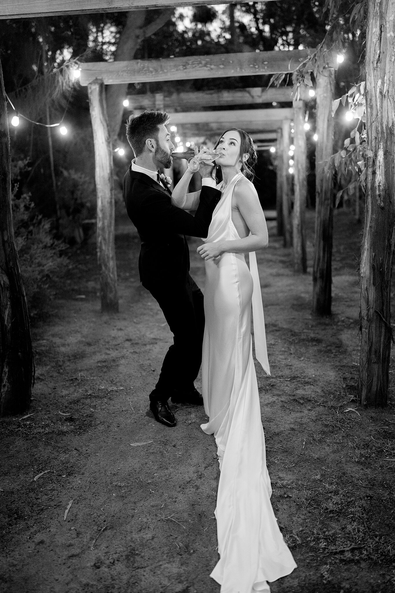 Emma and Dave dance along the timber pergola walkway, in black and white.
