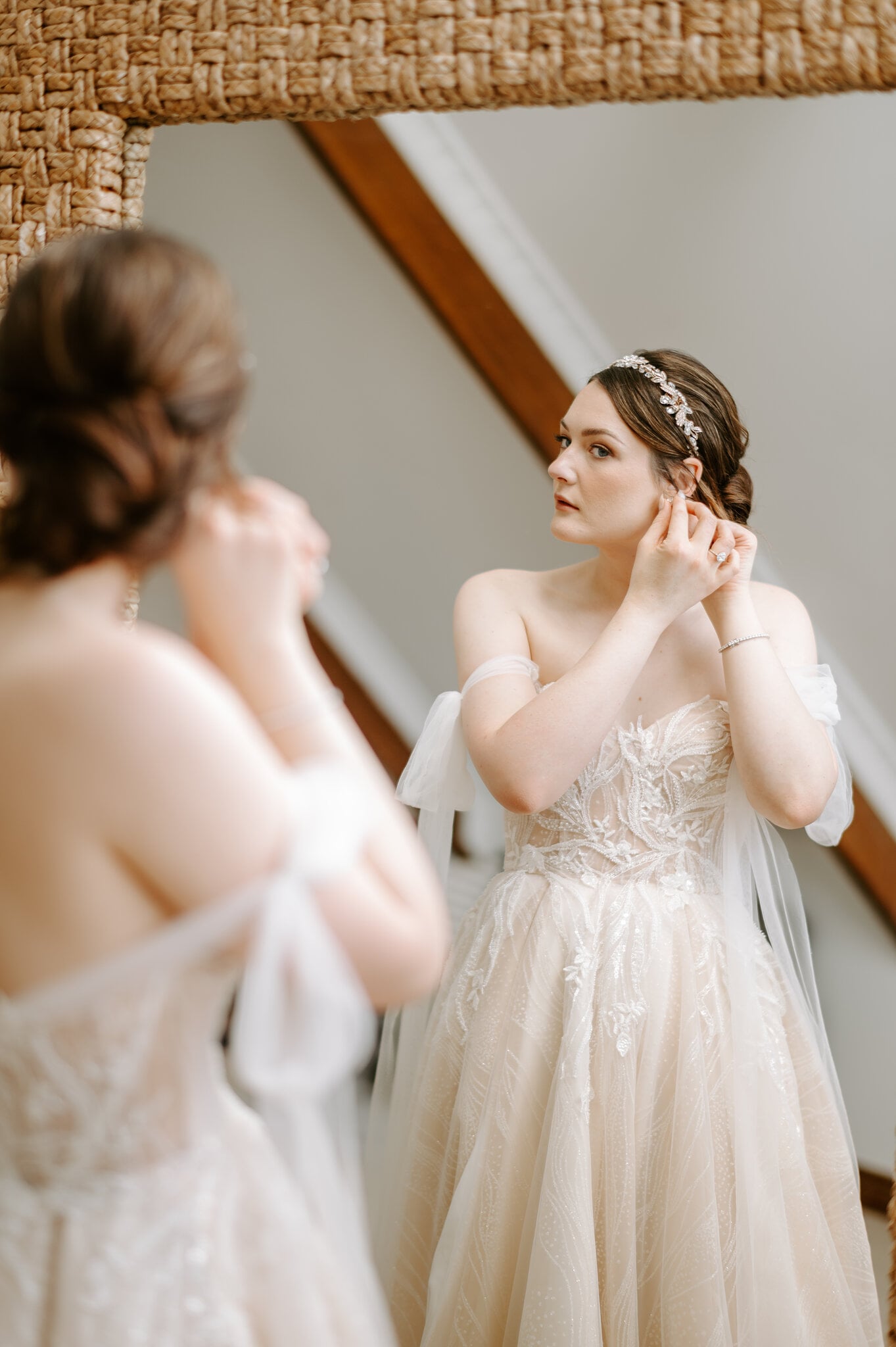 Jamie fastens an earring in a woven-frame mirror in the Loft at Maleny Manor.