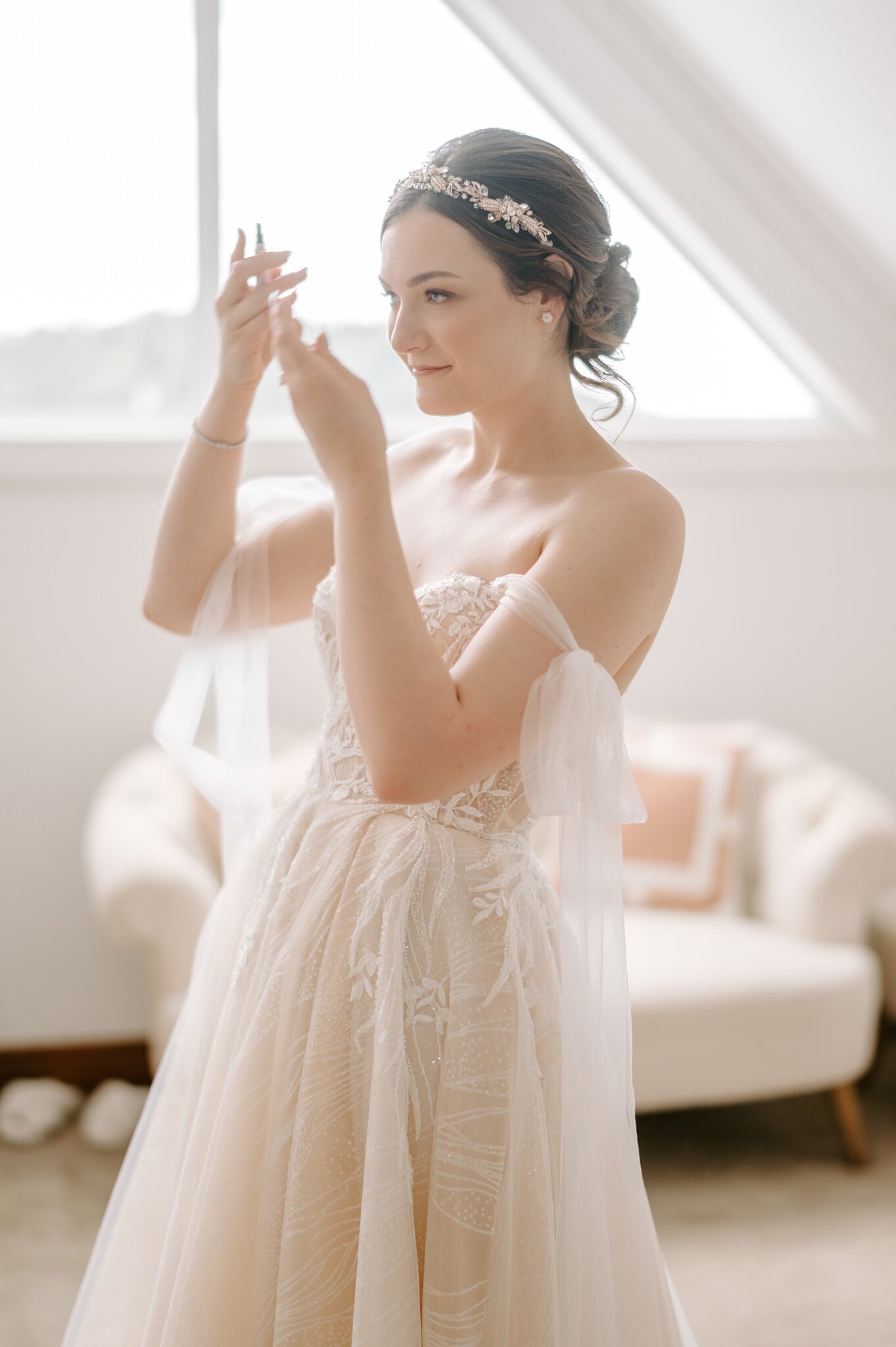 Jamie adjusts her earring by the gabled Loft window, wearing an off-the-shoulder blush gown and a crystal hair vine.