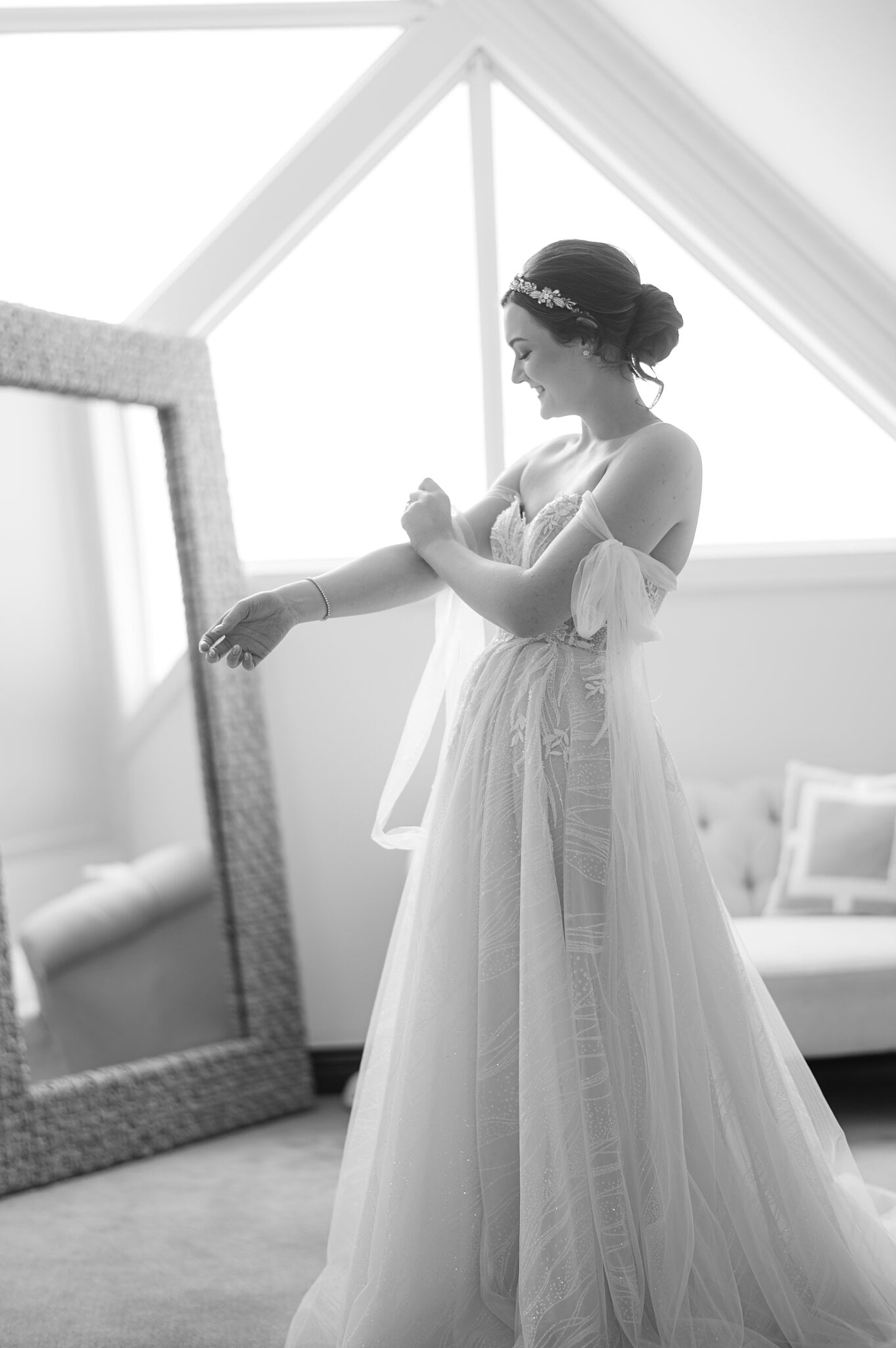 Jamie settles a tulle sleeve beside a tall mirror under the gabled Loft window.