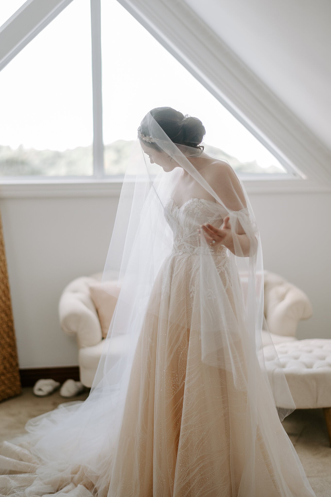 Jamie stands in her veil at the triangular Loft window, looking down at her gown.