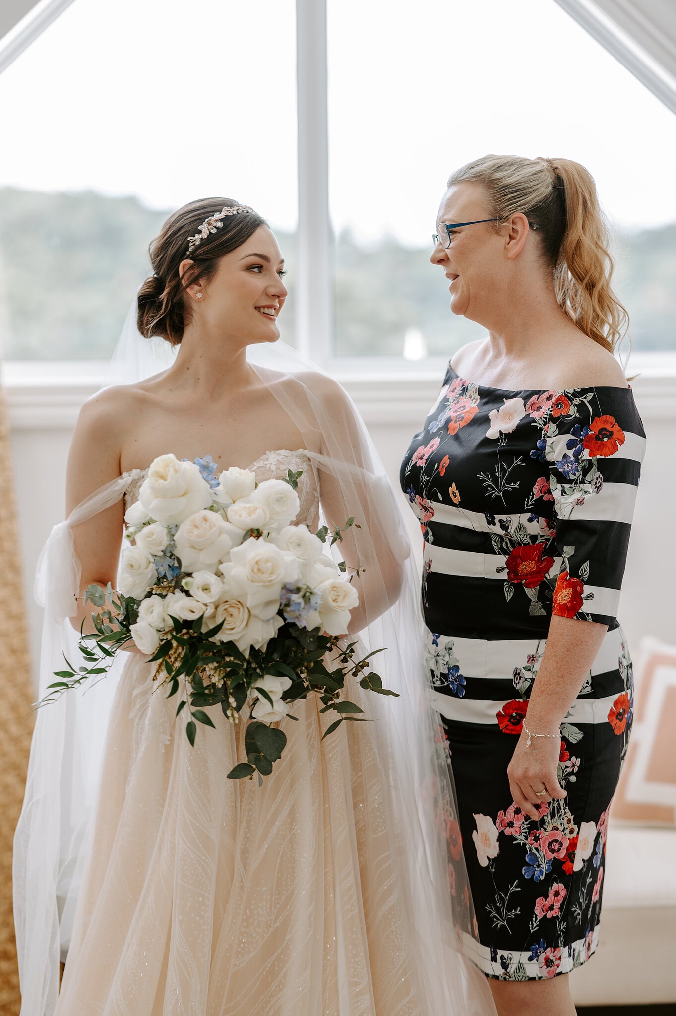Jamie holds her bouquet of white roses and smiles at her mum by the Loft window.