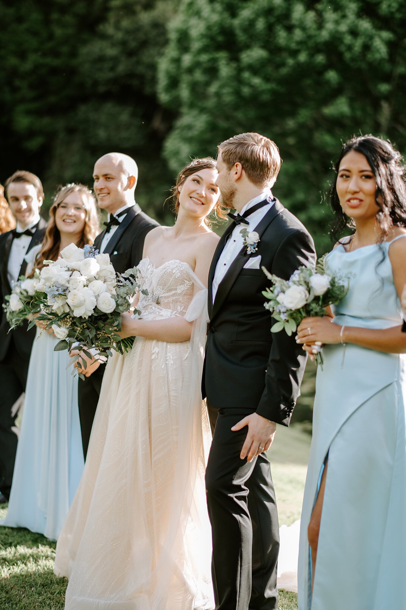 Jamie laughs with Tim and their bridal party lined up on the lawn.