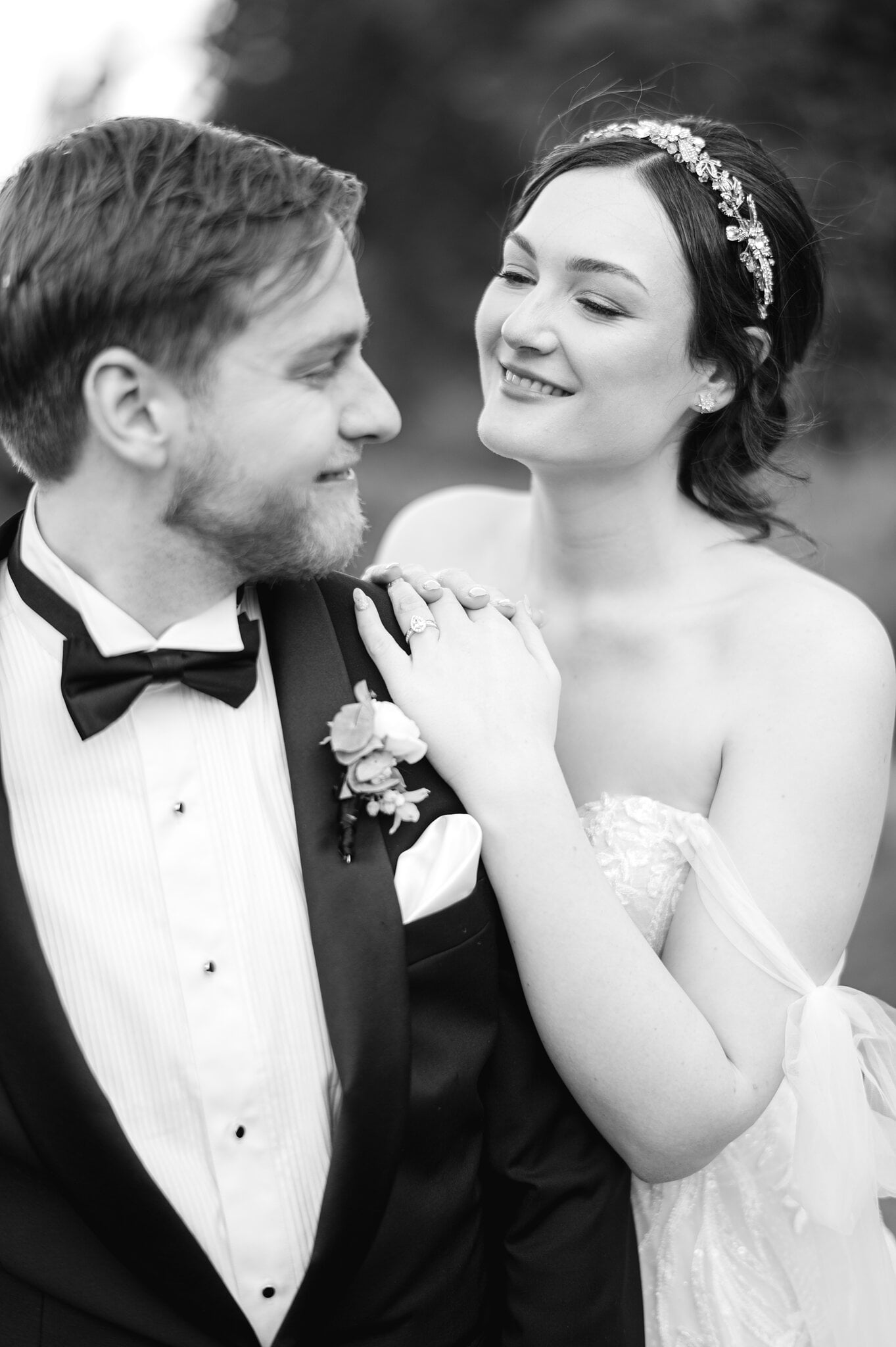 Jamie rests her hands on Tim’s shoulder and smiles up at him, in black and white.