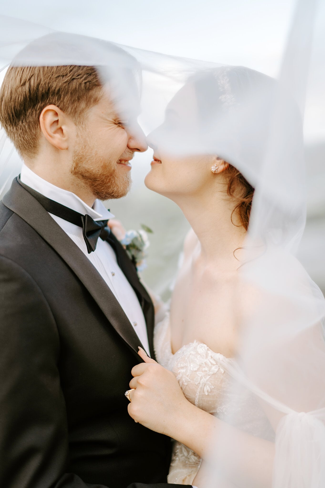Jamie and Tim stand nose to nose under her veil, both laughing.