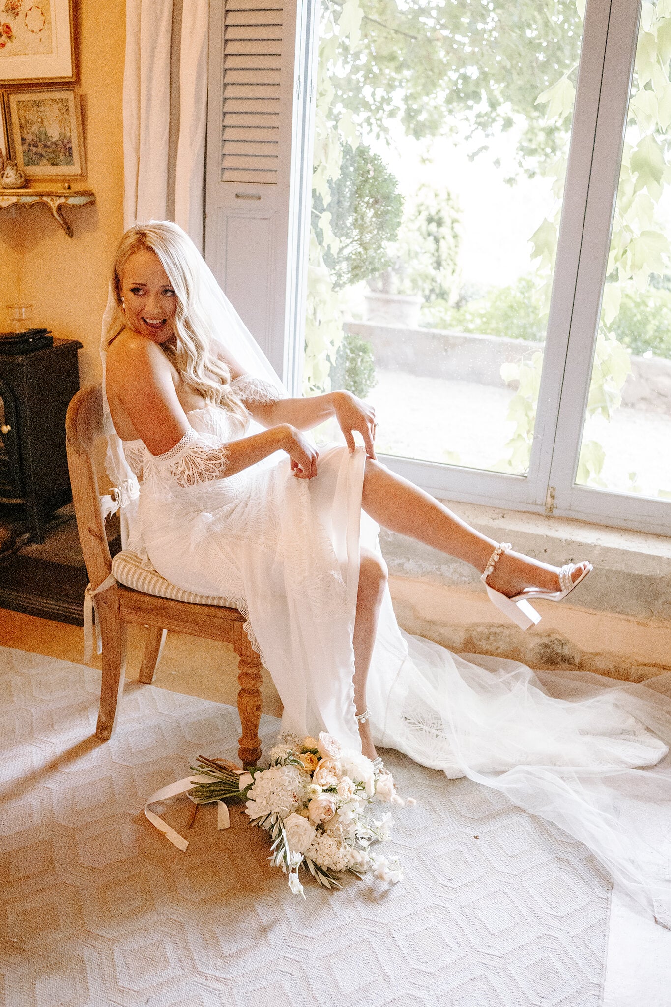 Samantha laughs on a vintage chair, one pearl-strapped heel kicked out from her lace gown.