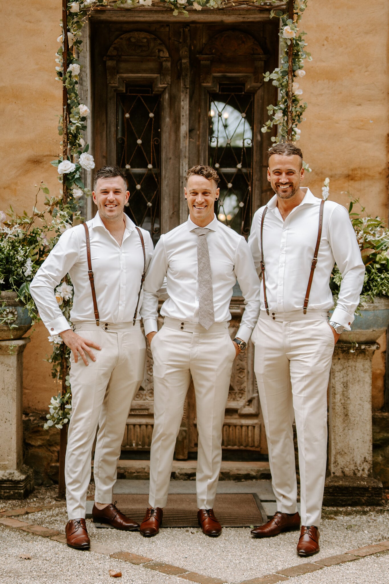 Harrison and his groomsmen in braces and cream trousers at the carved doors.