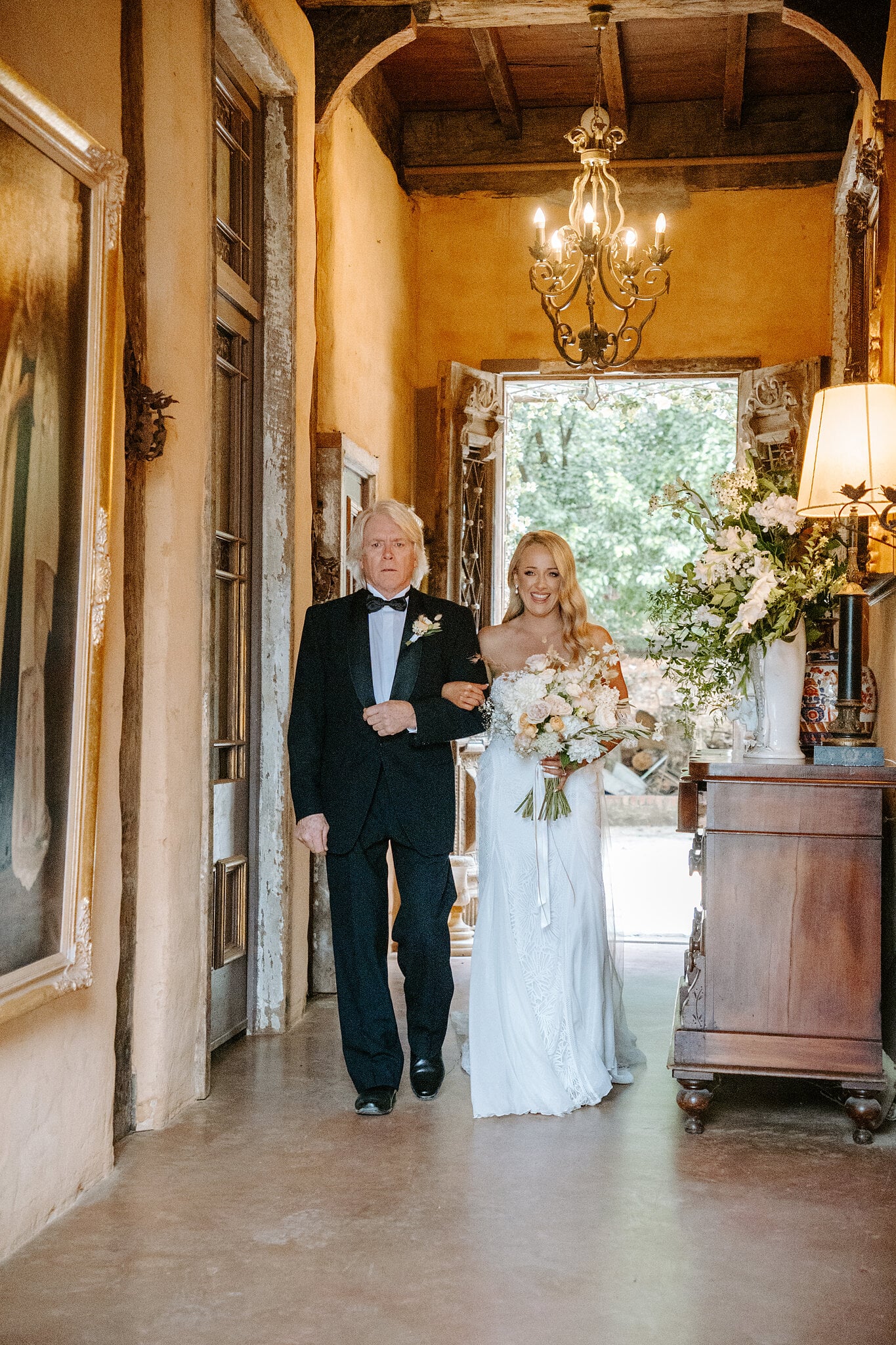 Samantha’s dad walks her down the chandelier-lit hallway towards the ceremony.
