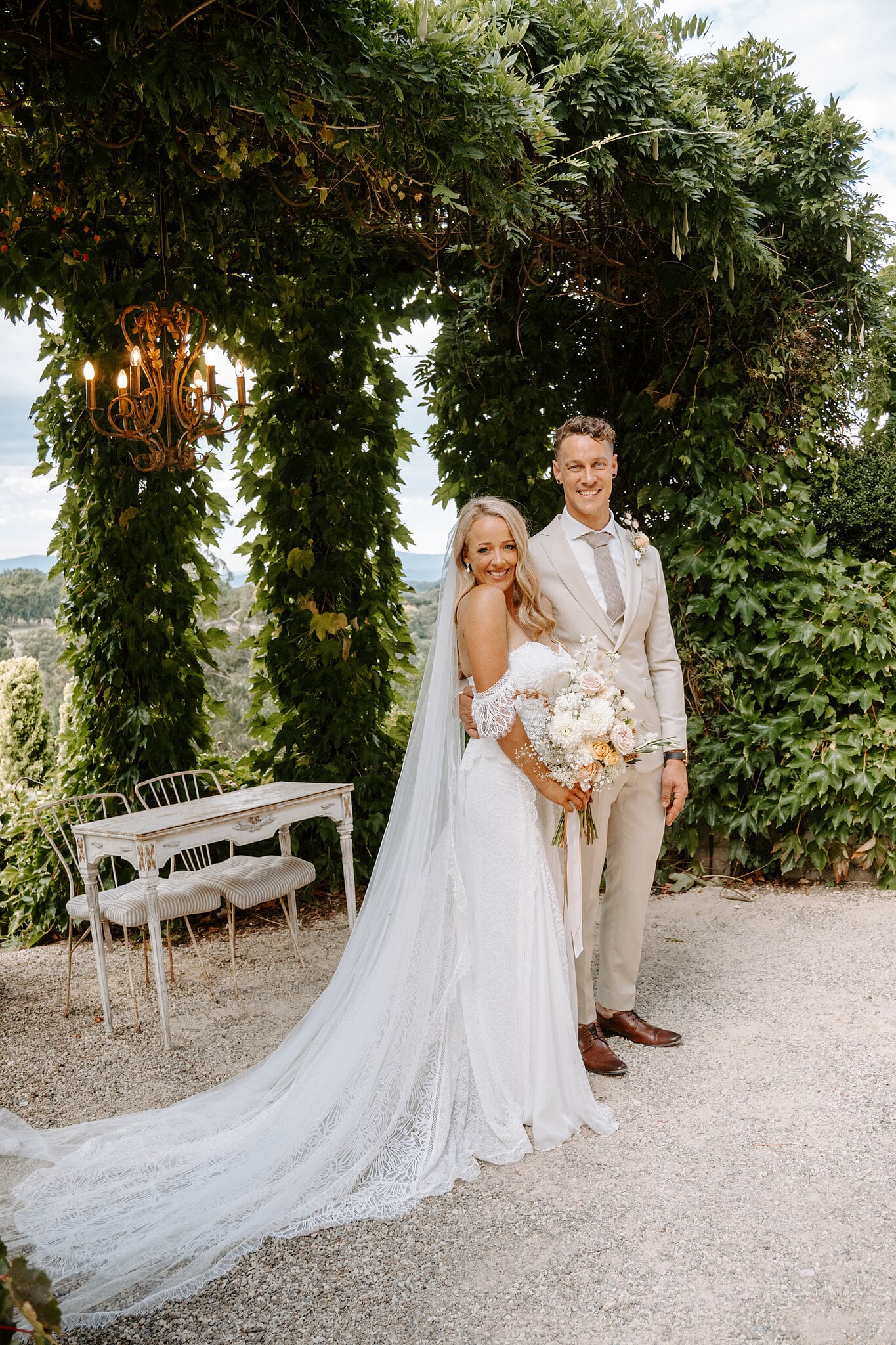 Samantha and Harrison under the arbour beside the white signing table and chairs.