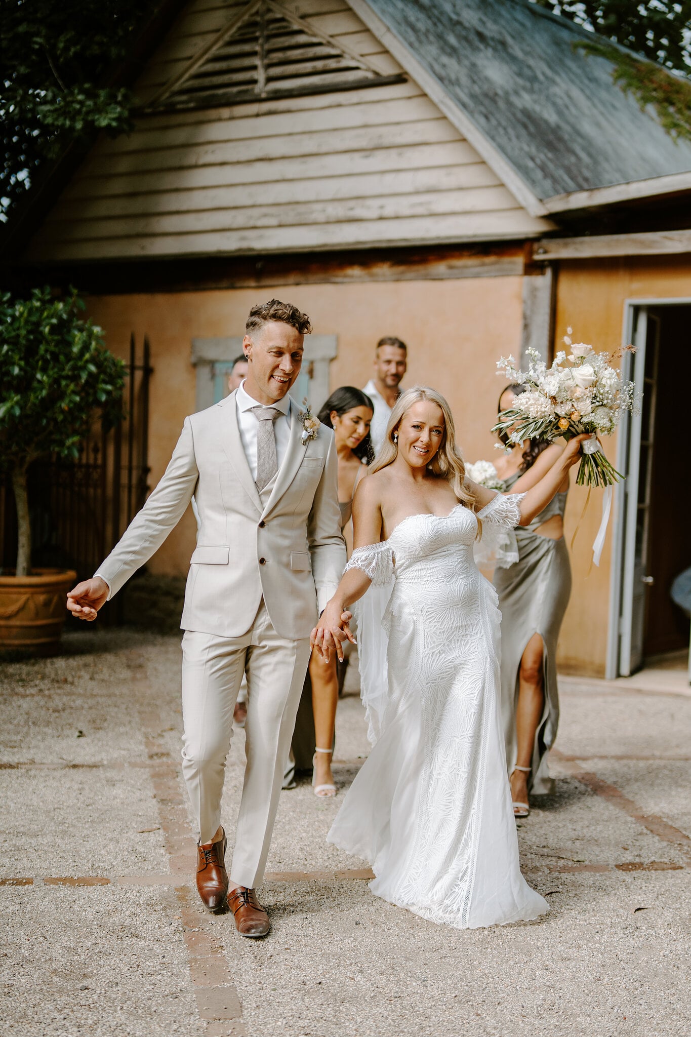 Samantha and Harrison stride out of the old timber stables with the bridal party behind.