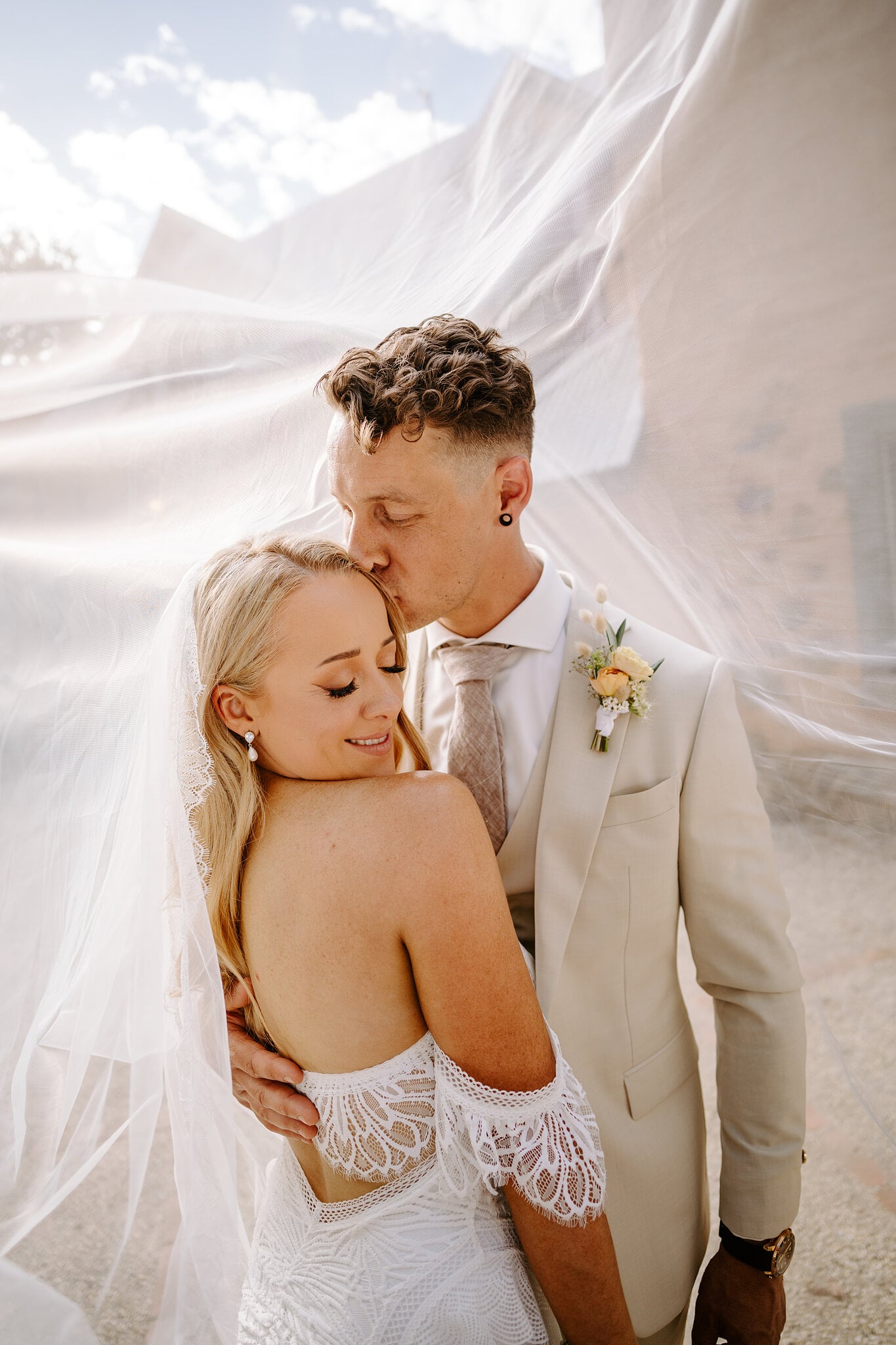 Harrison kisses Samantha’s forehead as her veil billows around them.