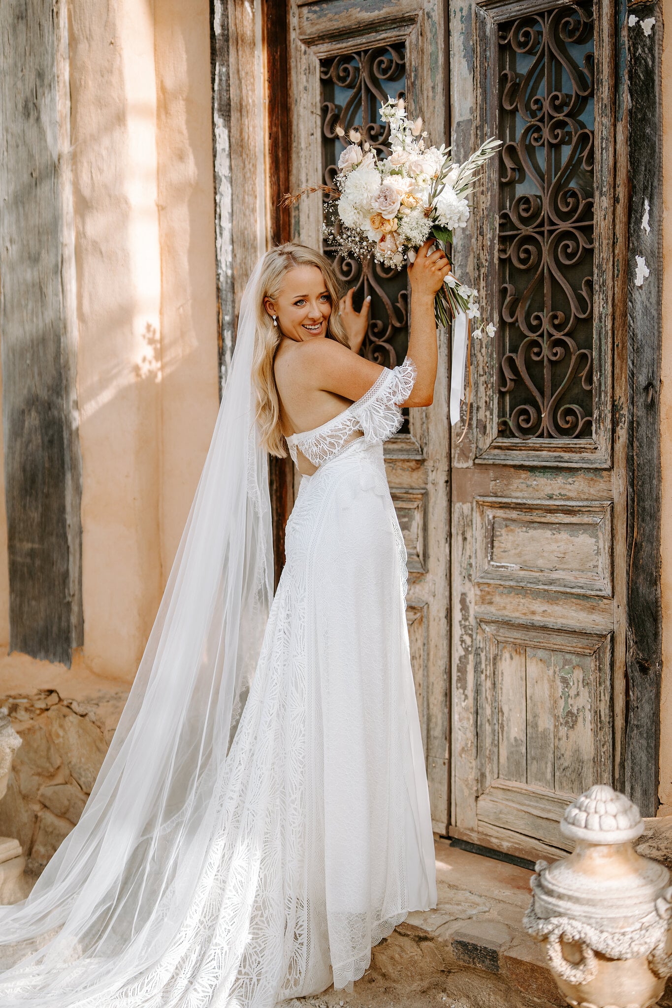 Samantha lifts her bouquet against the carved doors and wrought iron at Mont du Soleil.