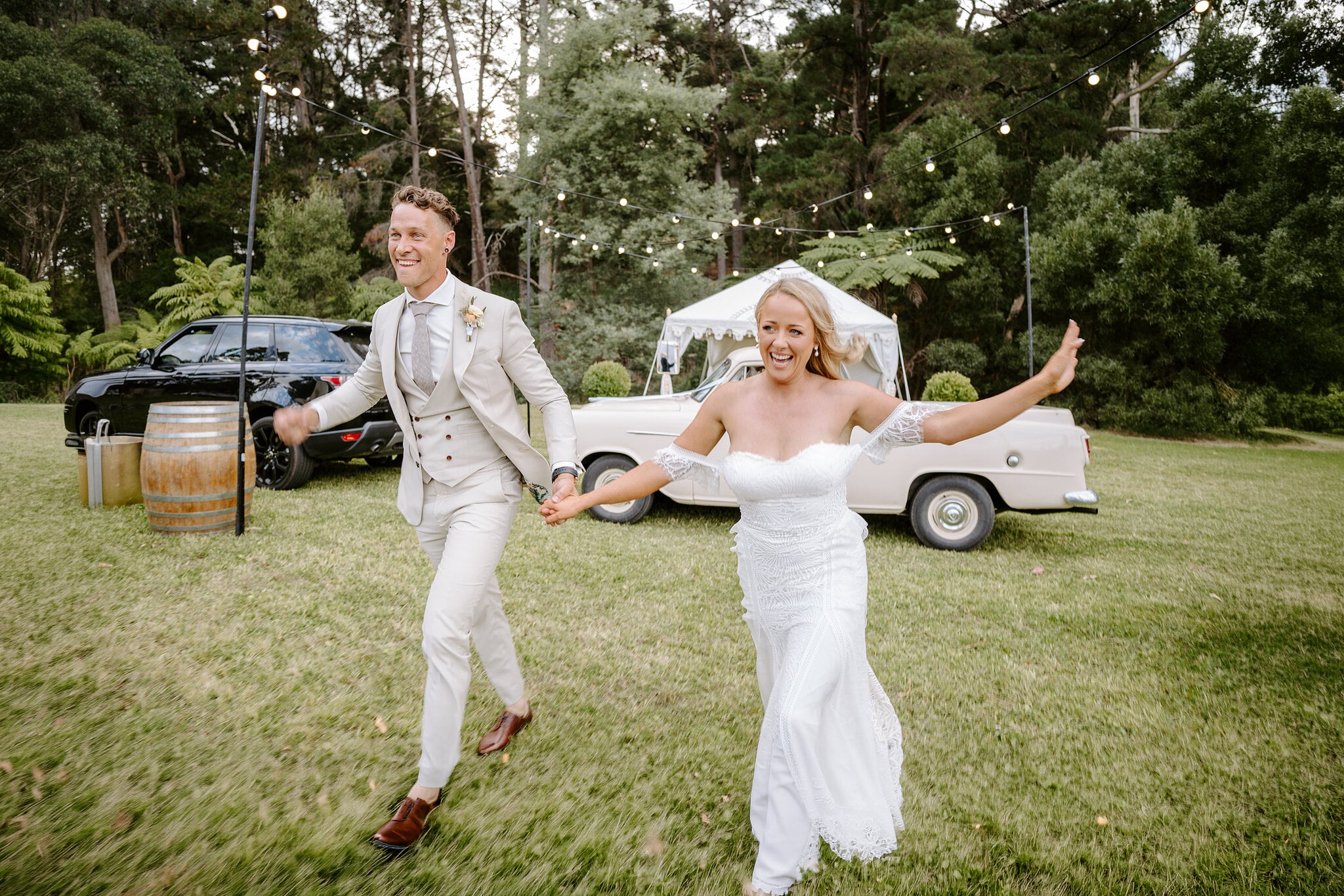 Samantha and Harrison run across the lawn past the vintage ute and marquee.