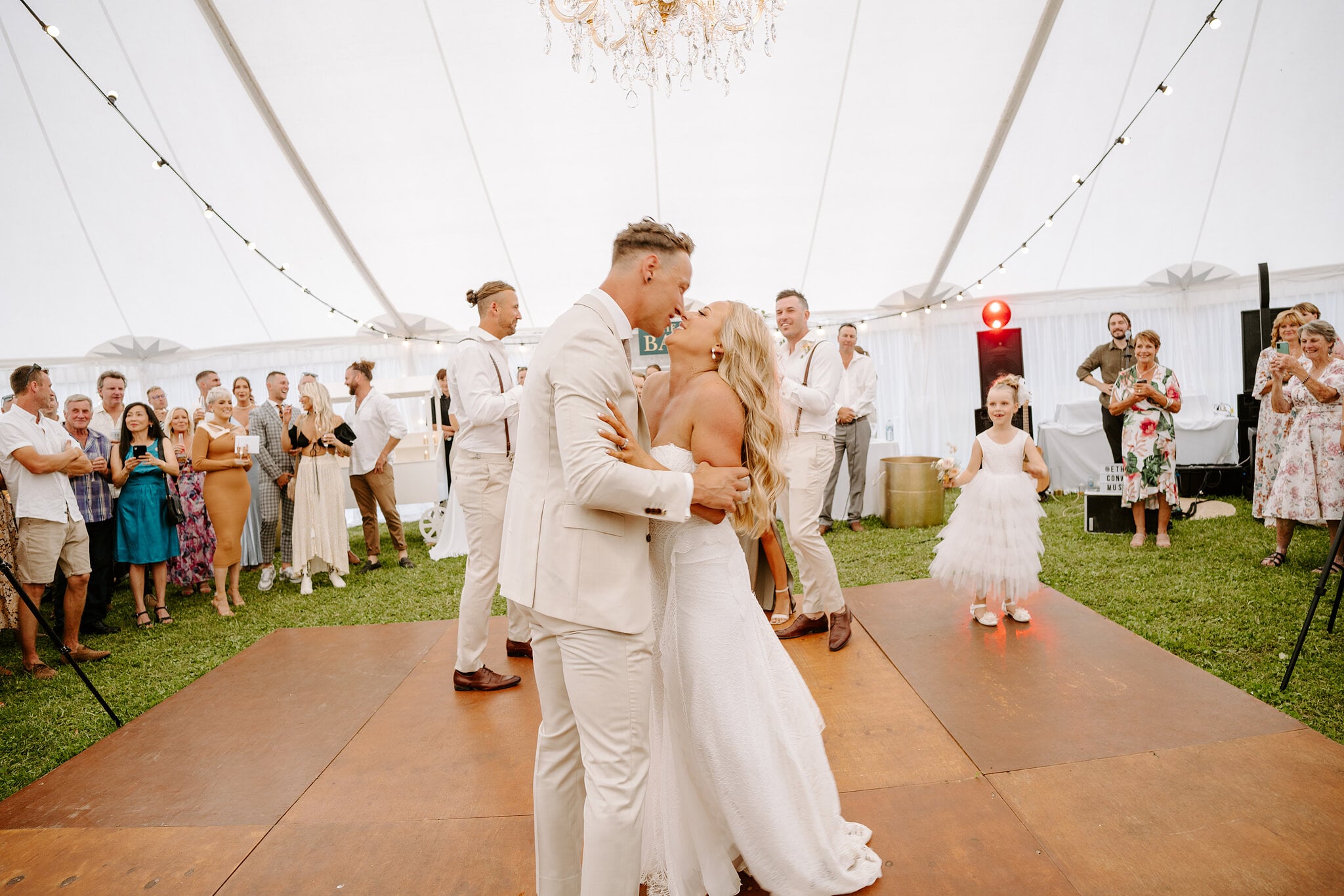 Samantha and Harrison kiss during their first dance as the flower girl watches.