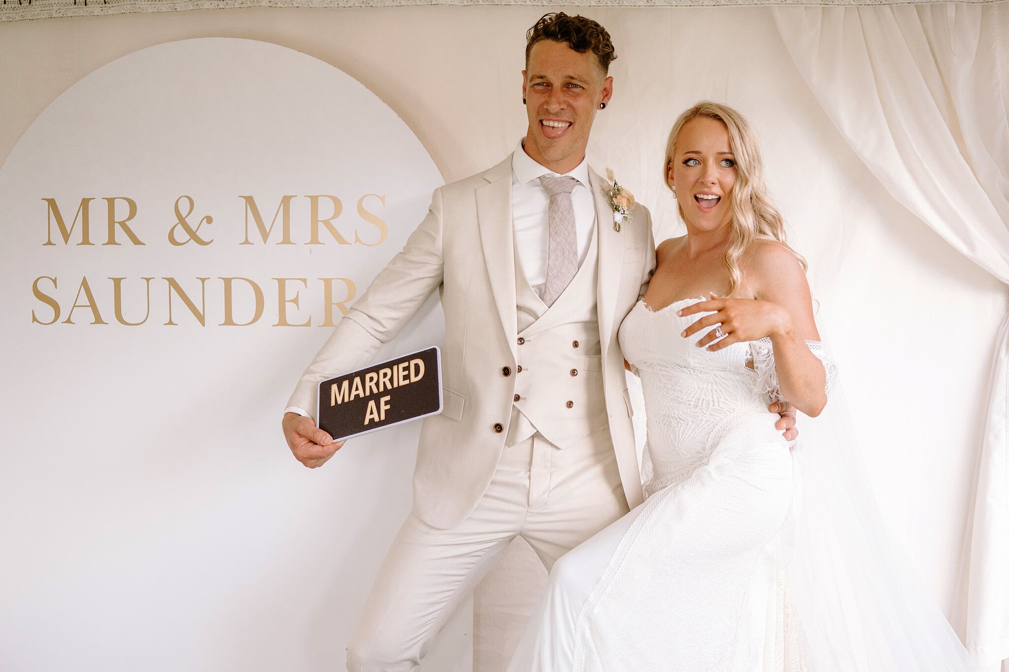 Harrison holds up a cheeky sign beside Samantha at the photo wall.