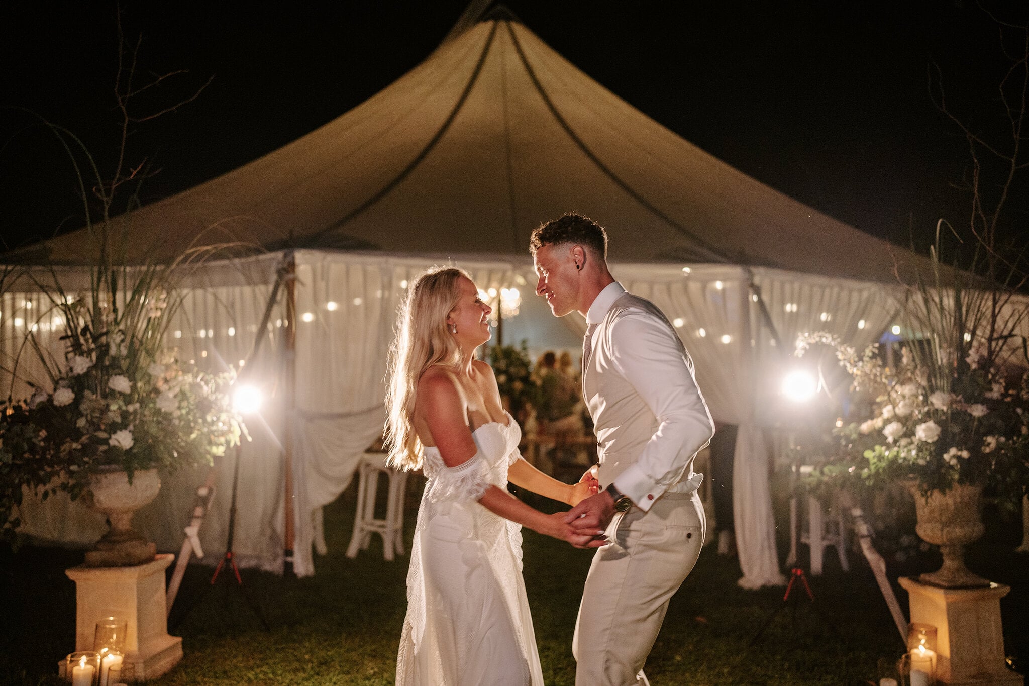 Samantha and Harrison dance on the lawn outside the glowing marquee at night.