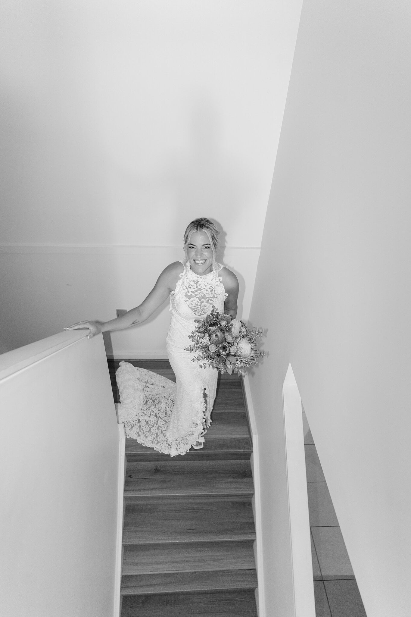 Emma comes down a white staircase in her lace gown, in black and white.