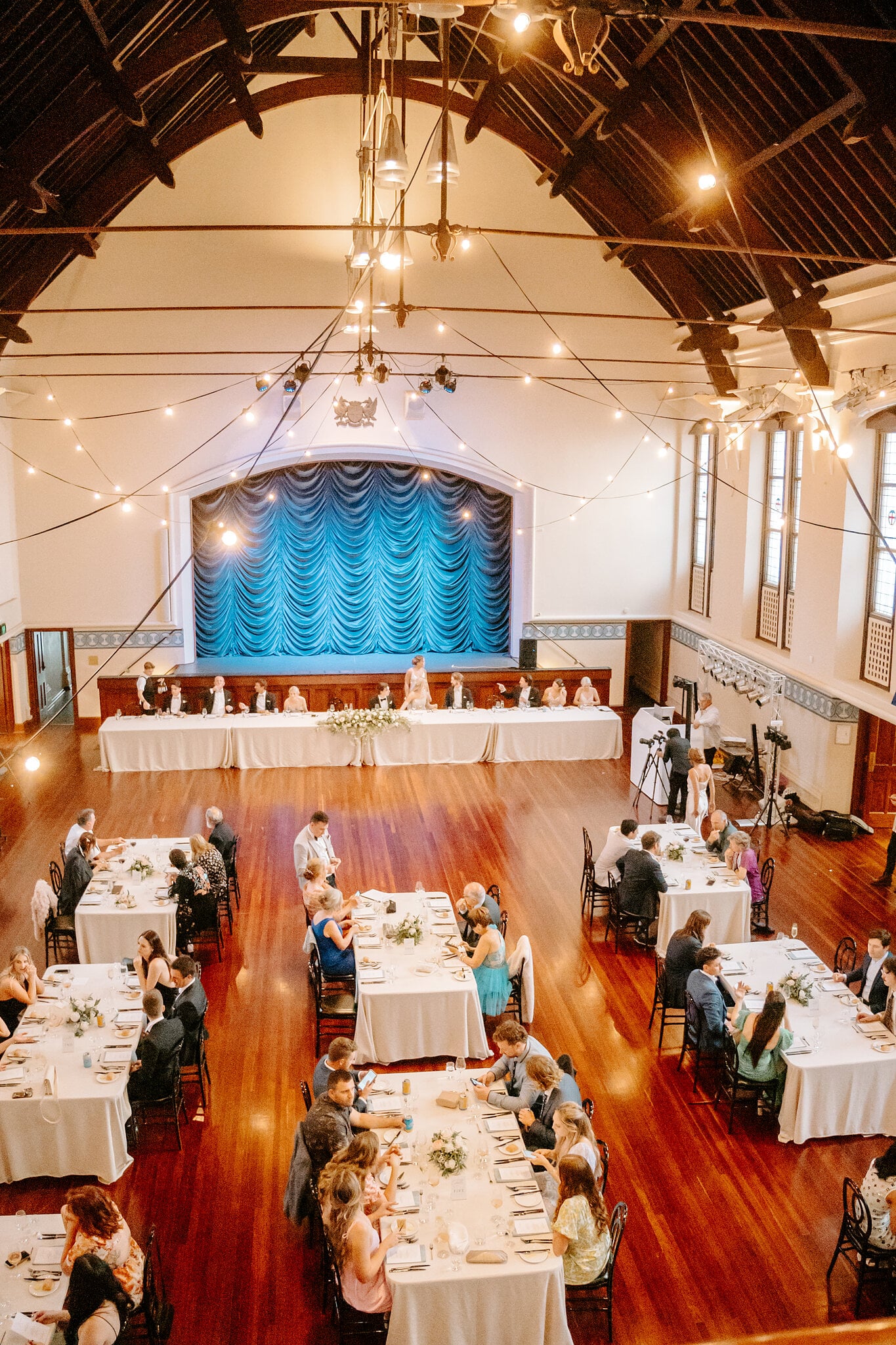 Festoon lights and long tables fill the Main Hall at Perth Town Hall, seen from above.