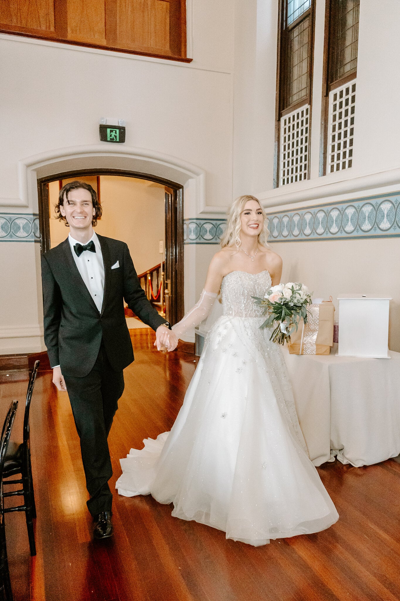Claire and George walk hand in hand through the arched doorway into their reception.