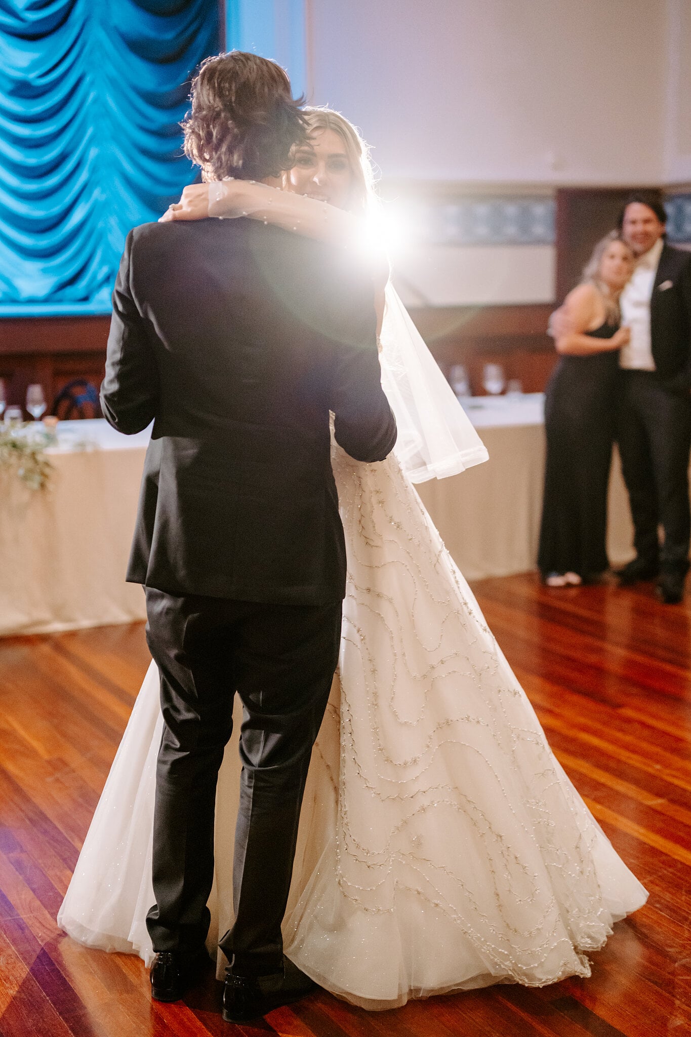 Claire wraps her arms around George’s neck as a light flares behind them on the jarrah floor.