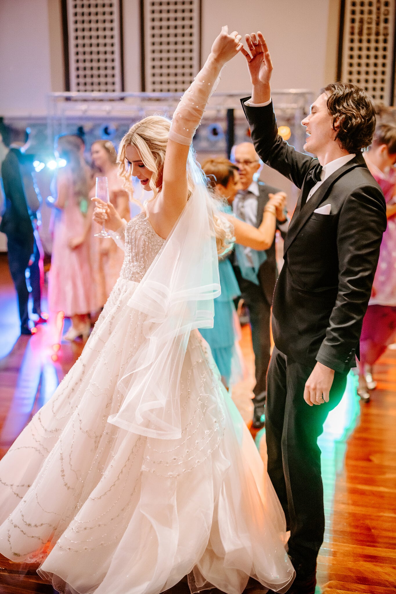 Claire twirls under George’s arm, champagne in hand, as the dance floor fills with colour.