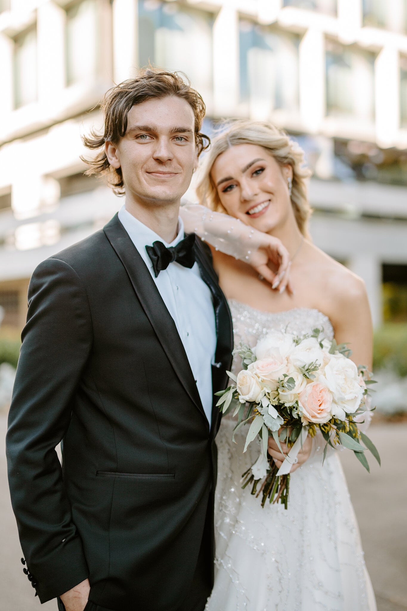 Claire drapes an arm over George’s shoulder as both grin at the camera in the city.