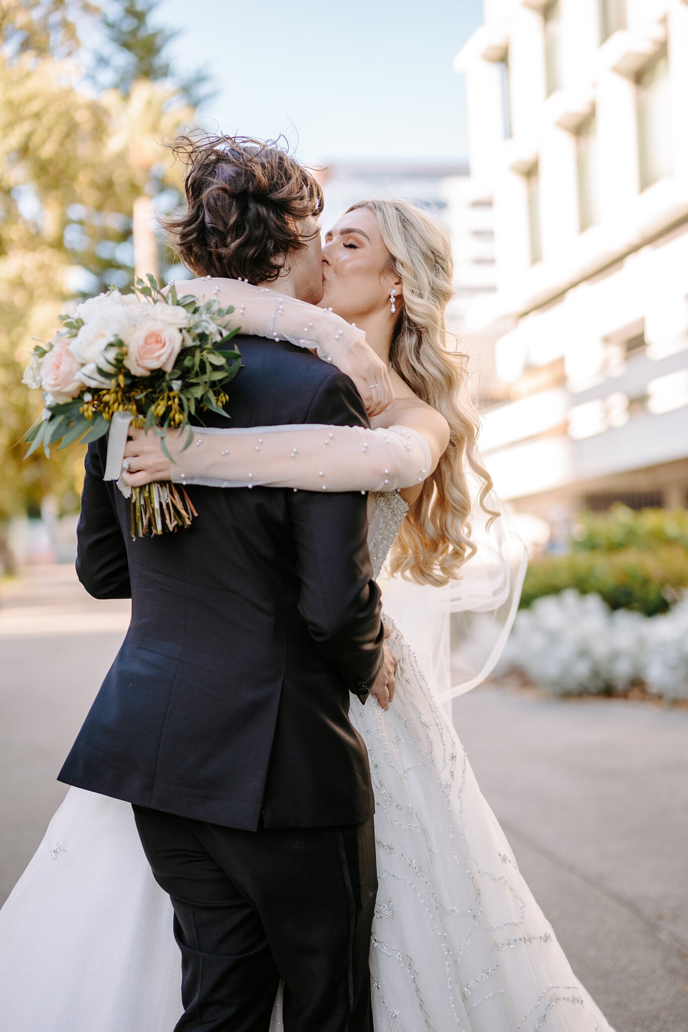 Claire wraps her sheer pearl sleeves around George for a kiss on a city street.