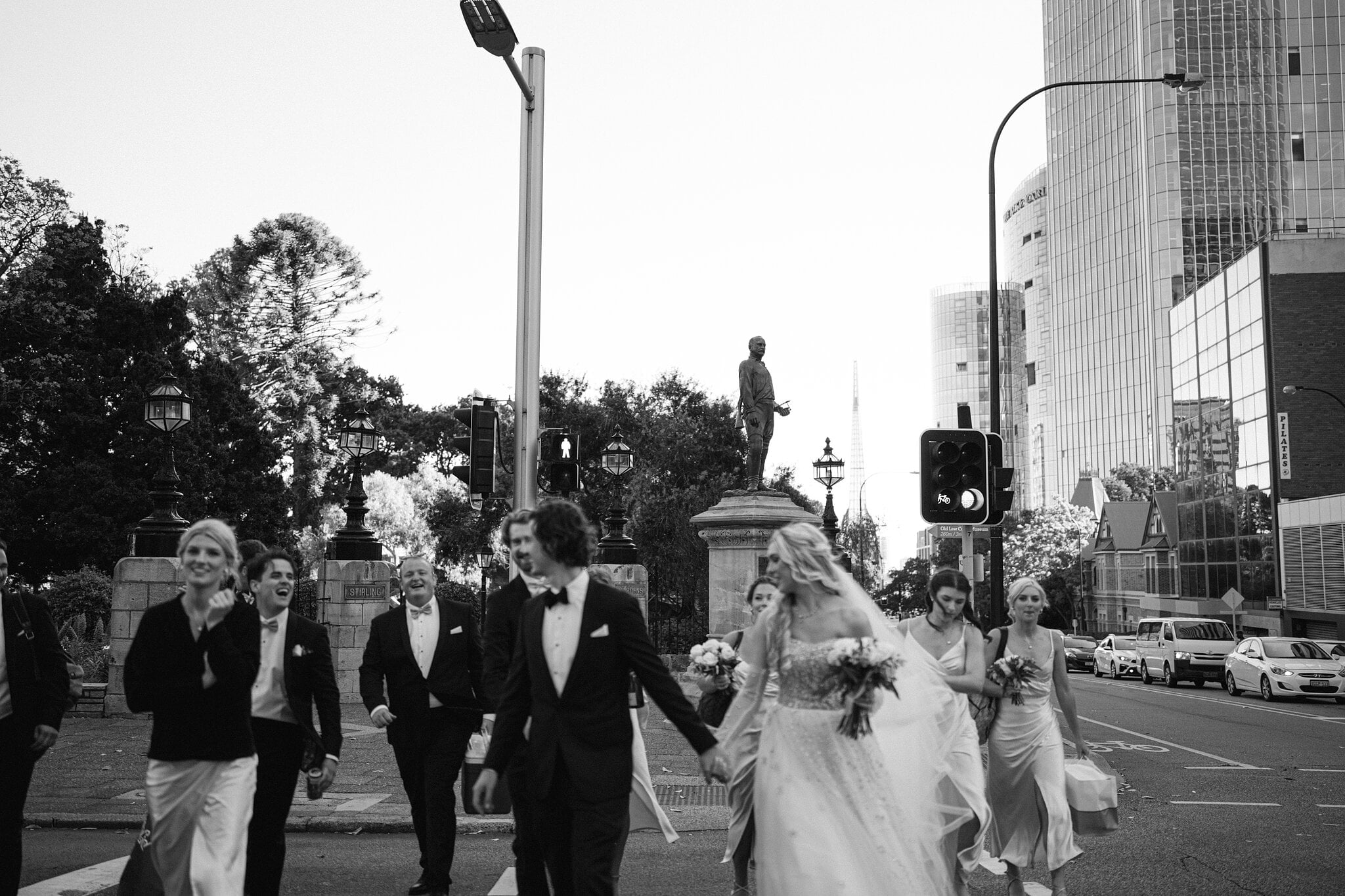 Black and white of the bridal party crossing a city street hand in hand towards the Town Hall.