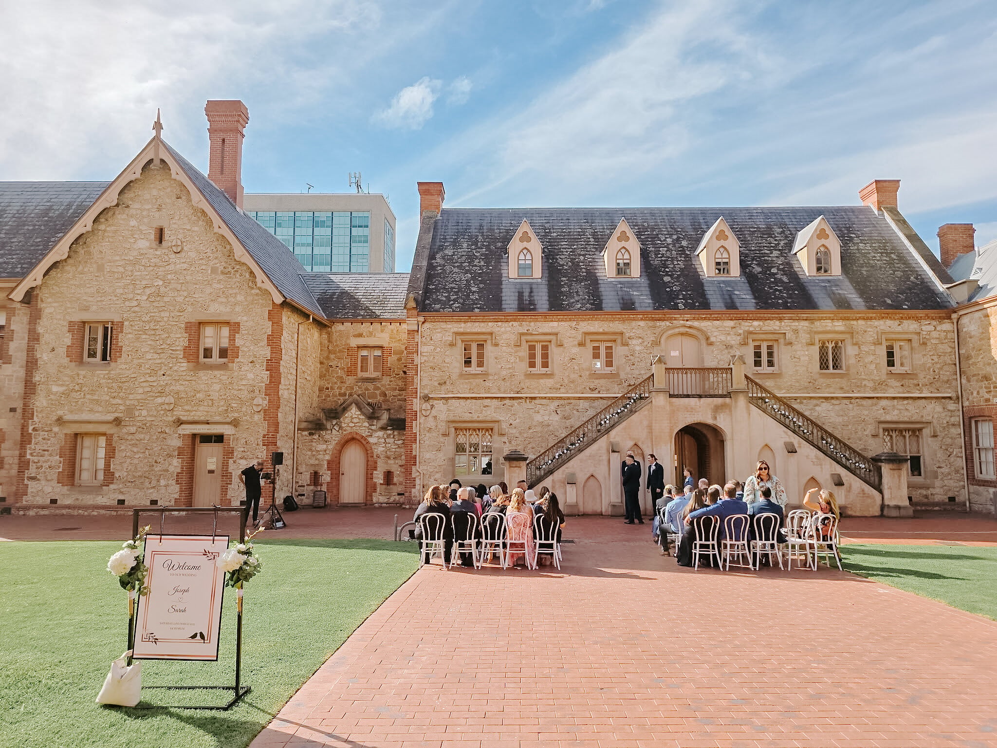 A welcome sign stands on the lawn as guests take their seats on white chairs in the Armoury courtyard.