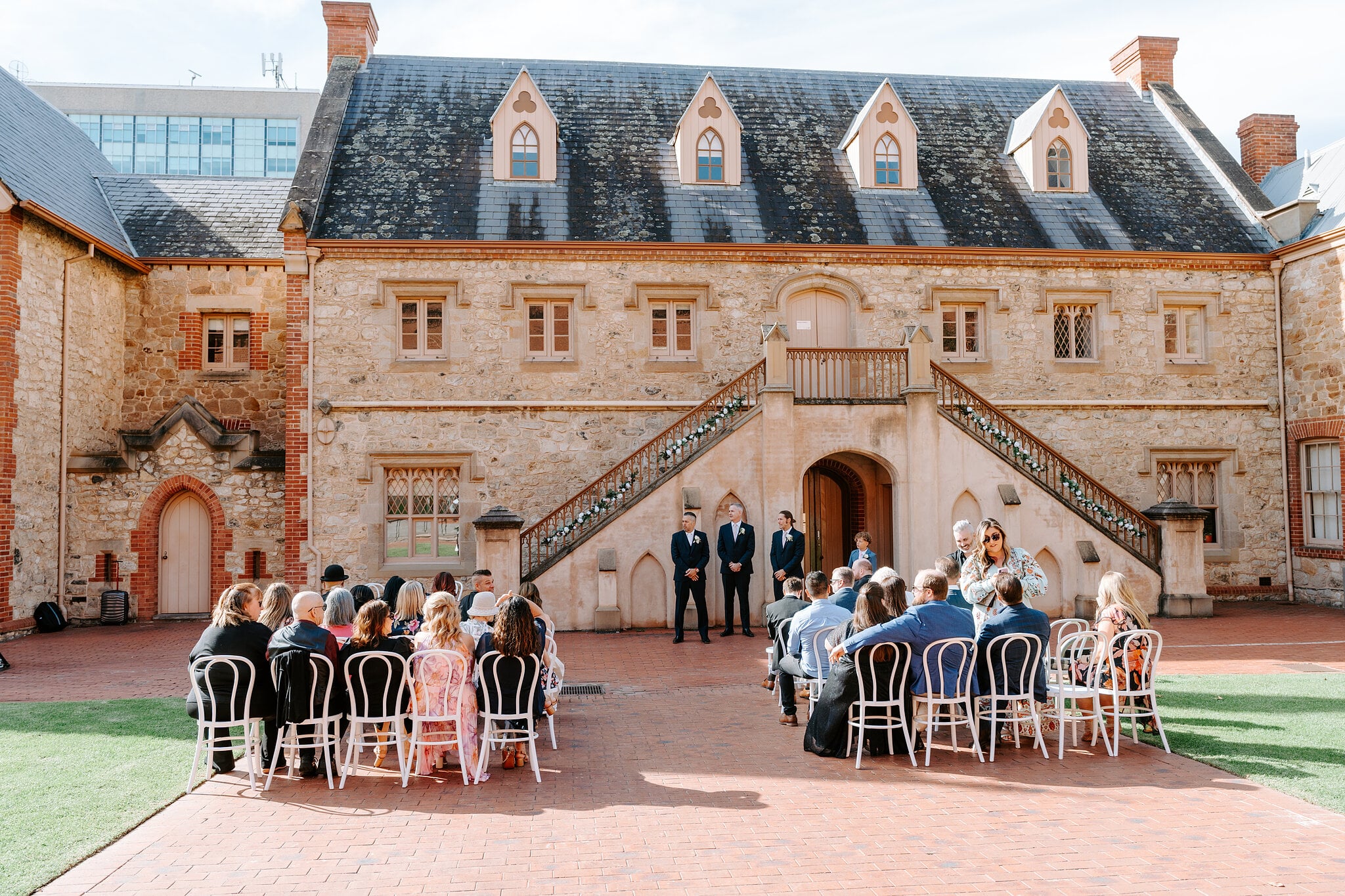 Joe waits with his groomsmen under the twin staircase as guests settle into their seats.
